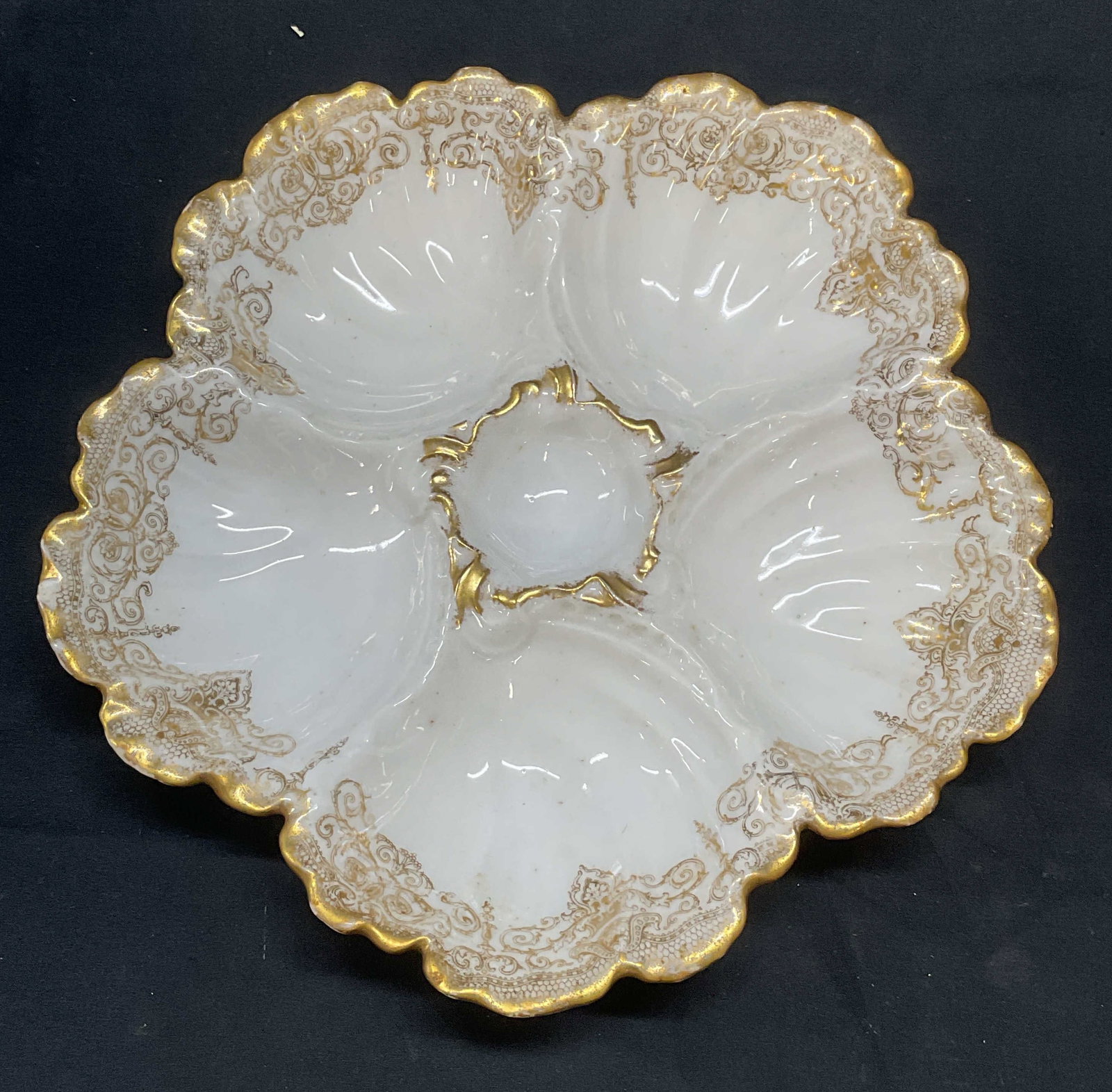 Vntg A. K. Limoges Porcelain Oyster Plate, France: Vintage A. K. Limoges porcelain oyster plate. Gilt decoration with scroll pattern. Scalloped rim. Wells for 5 oysters. Trademarked to underside. Made in France. Measures approx. 9 inches wide. Some su