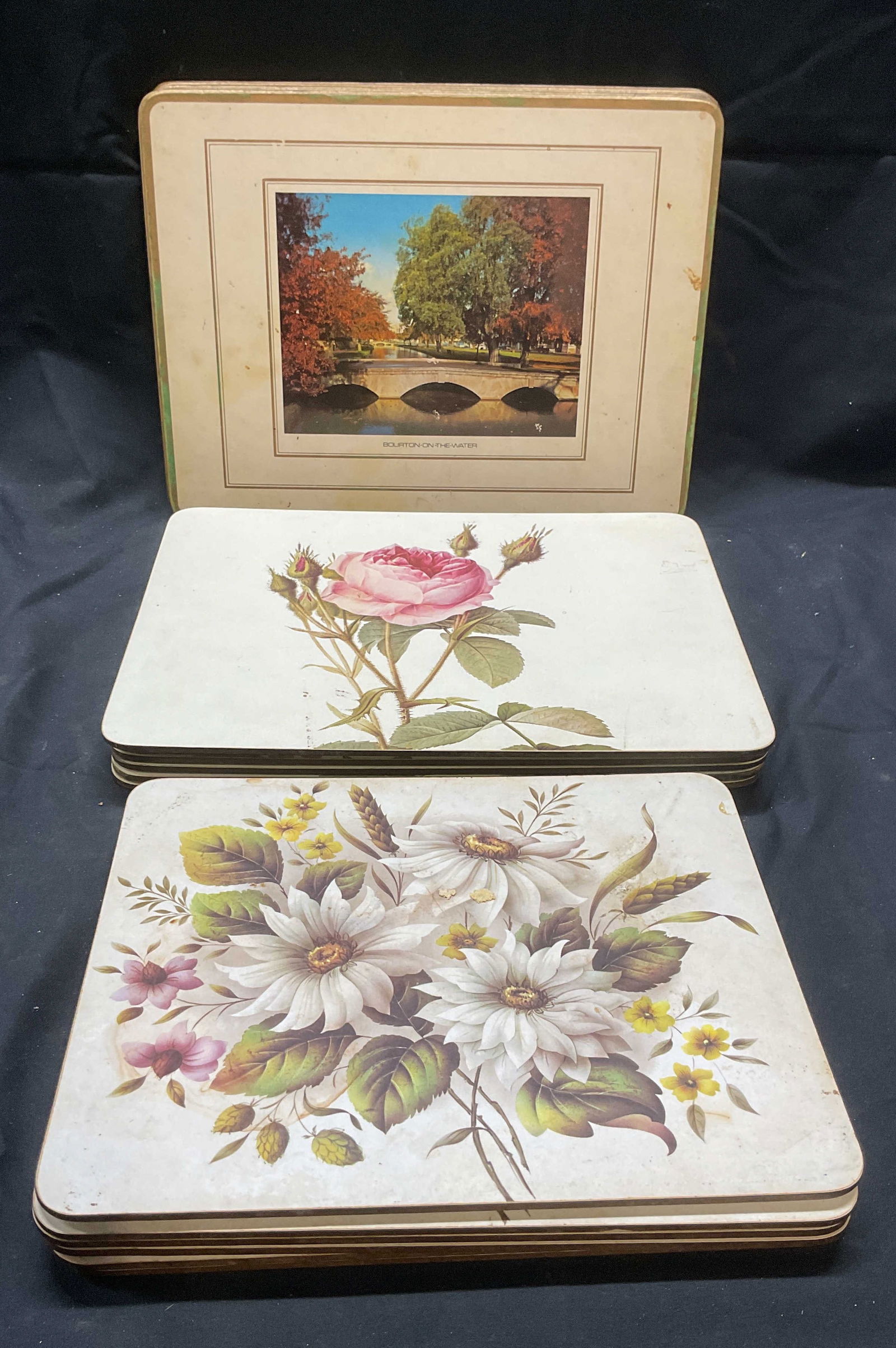 Group 18 Wood Floral & Countryside Placemats: Group of 18 wood particle board placemats. 6 with white floral motif, 6 with 3 unique floral motifs, and 6 with unique English countryside motifs. Largest measure approx. 9 x 12 inches each. All piece