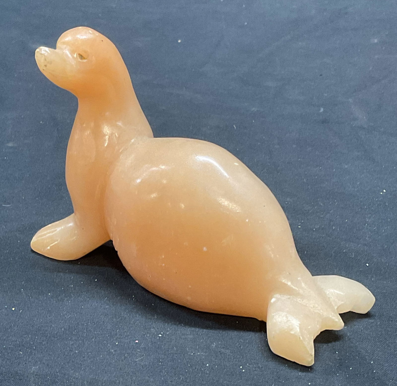 Hand Carved Orange Stone Seal Figural: Hand carved orange toned stone seal motif figural. Possibly alabaster. Measures approx. 4.75 x 1.75 x 3.25 inches. Some surface wear including scratching observed. Seal, stone seal, seal figural, coll