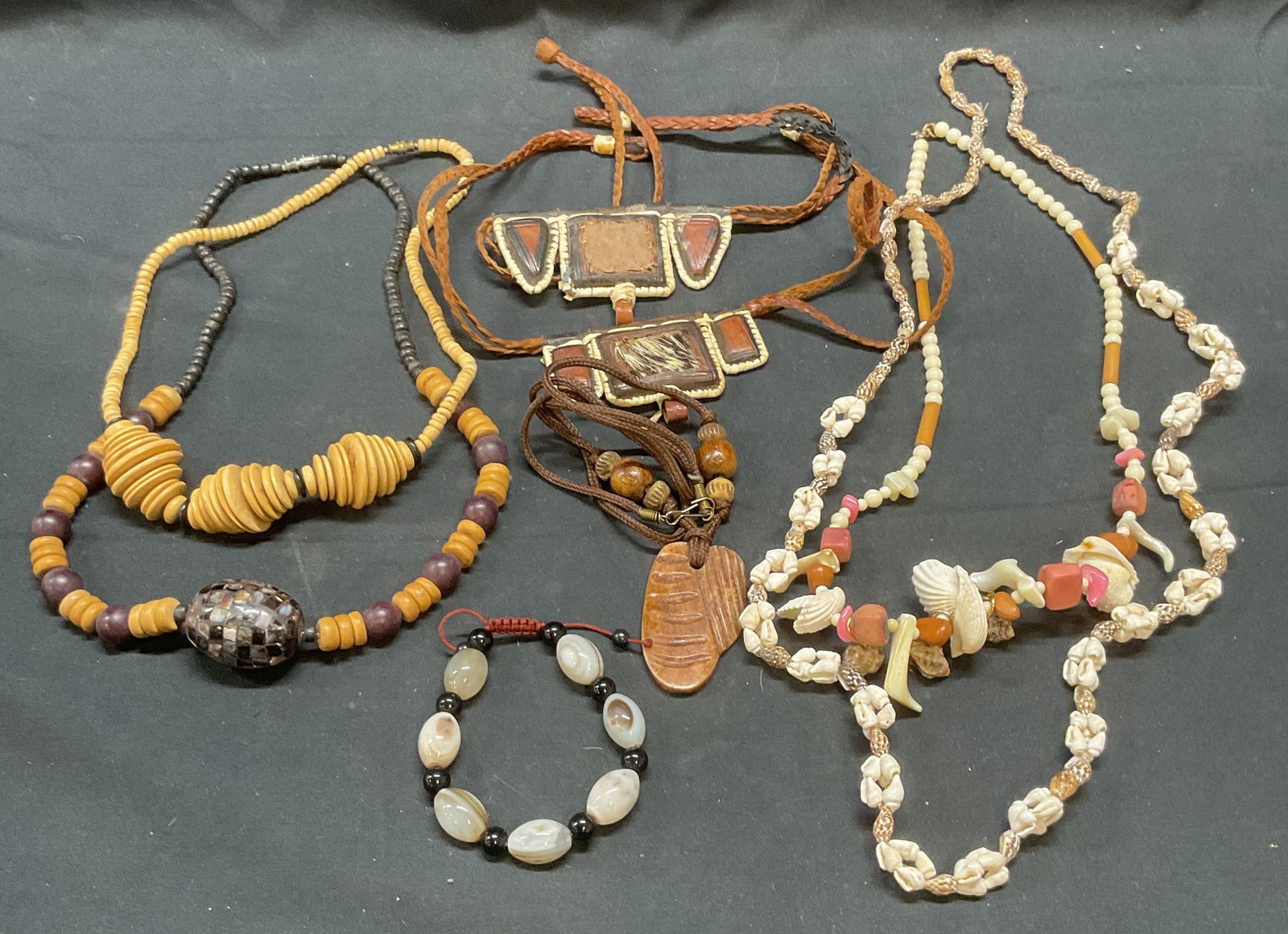 Lot 8 Leather, Shell, Wood Beaded Necklaces +: Lot of 8 jewelry pieces. Includes 2 leather necklaces, 2 wood and natural stone beaded necklaces, 1 necklace with disc beads, appears to be bone, 2 necklaces with shell and mother of pearl beads, and
