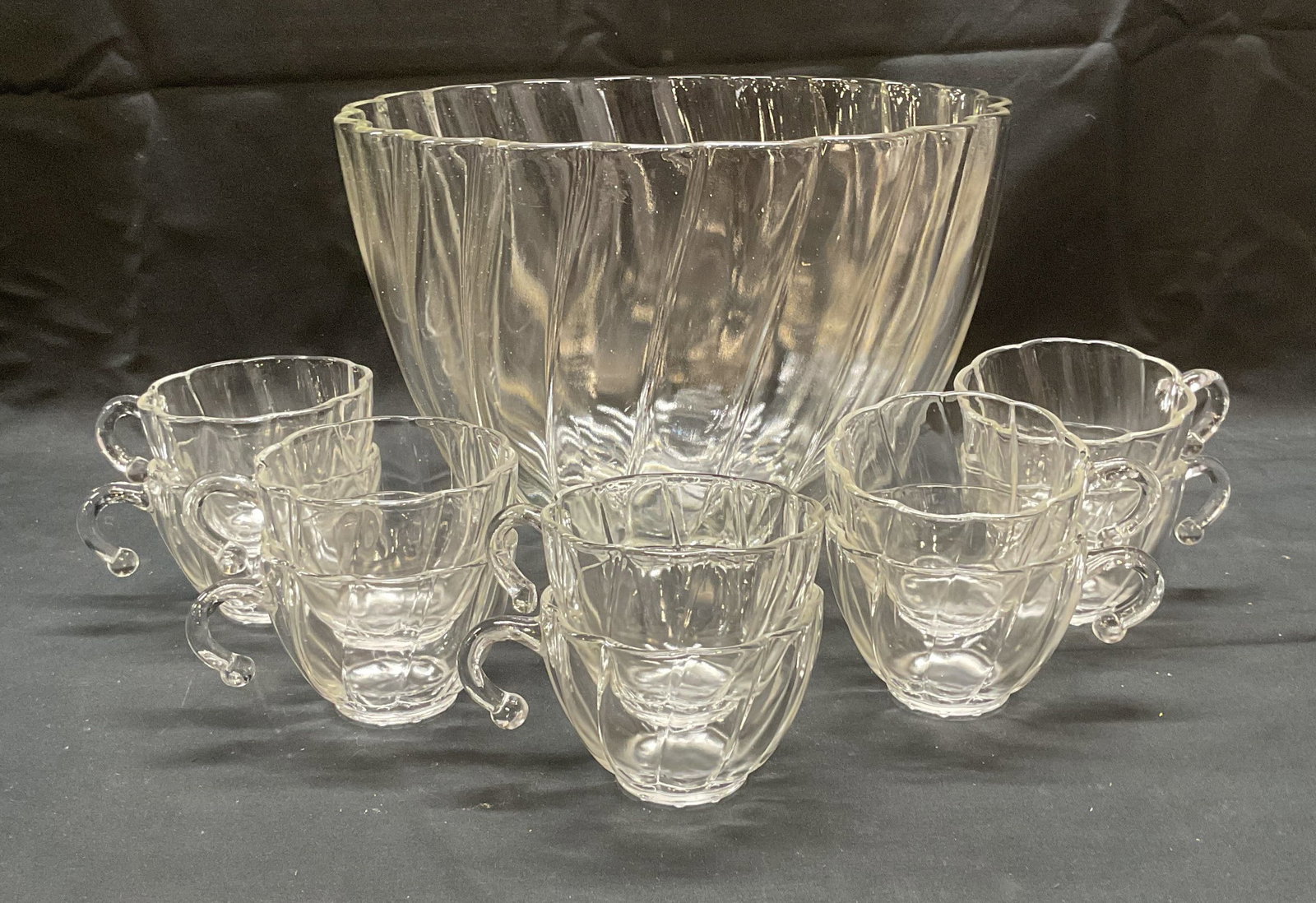 Set 11 Glass Punch Bowl & Glass Cups: Set of 11 pieces. Glass punch bowl with scalloped rim and raised swirling pattern and 10 matching cups with handles. Cups measure approx. 3.25 x 2.25 inches each. Bowl measures approx. 10.5 x 7 inches