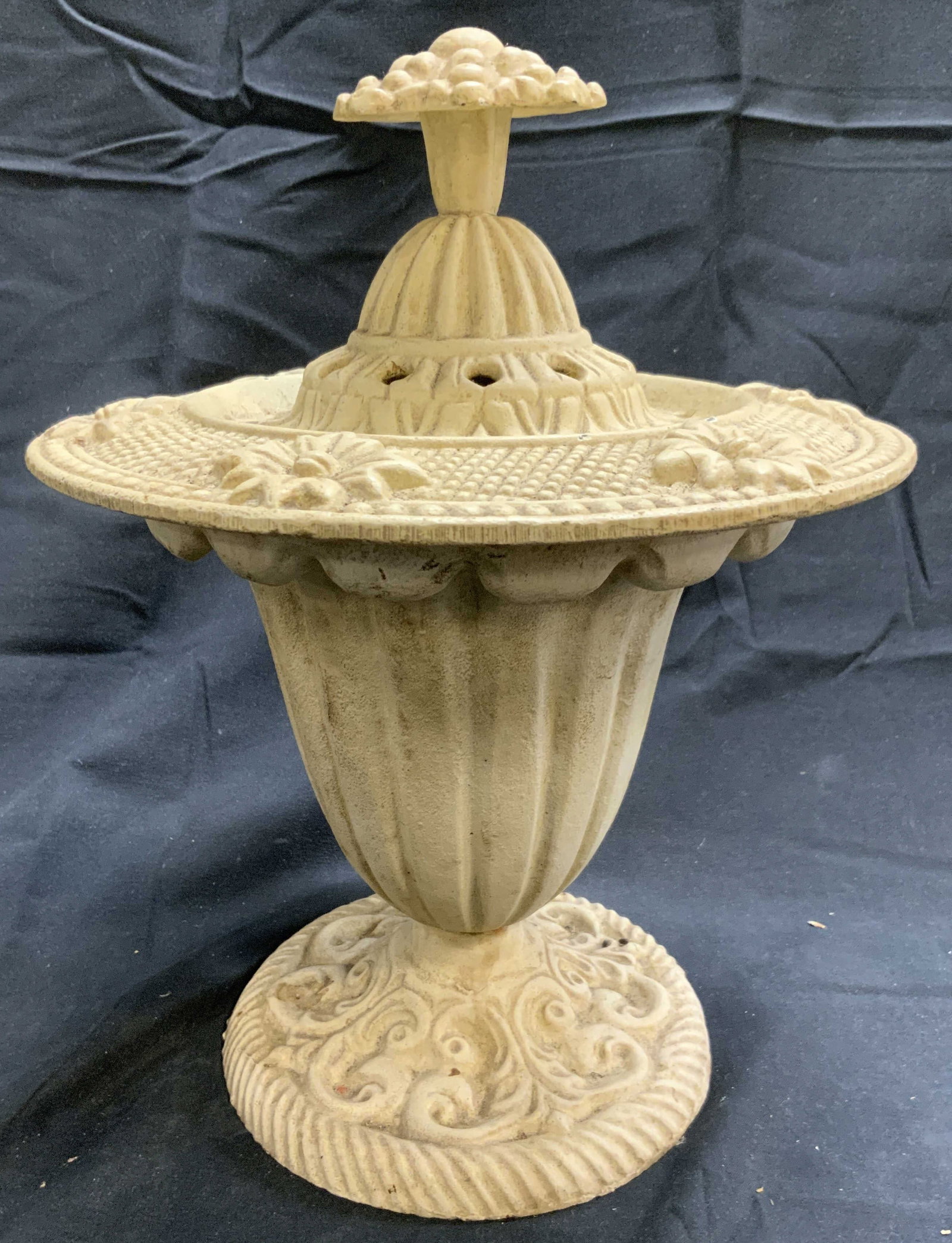 HEN FEATHERS Cast Iron Urn W Lid: Tag on underside and underside of lid reads HEN FEATHERS. Urn is cream toned. Piece is cast iron. Urn is scalloped. Piece has lid with pierced detail. Center of lid has floral form. Piece measures app