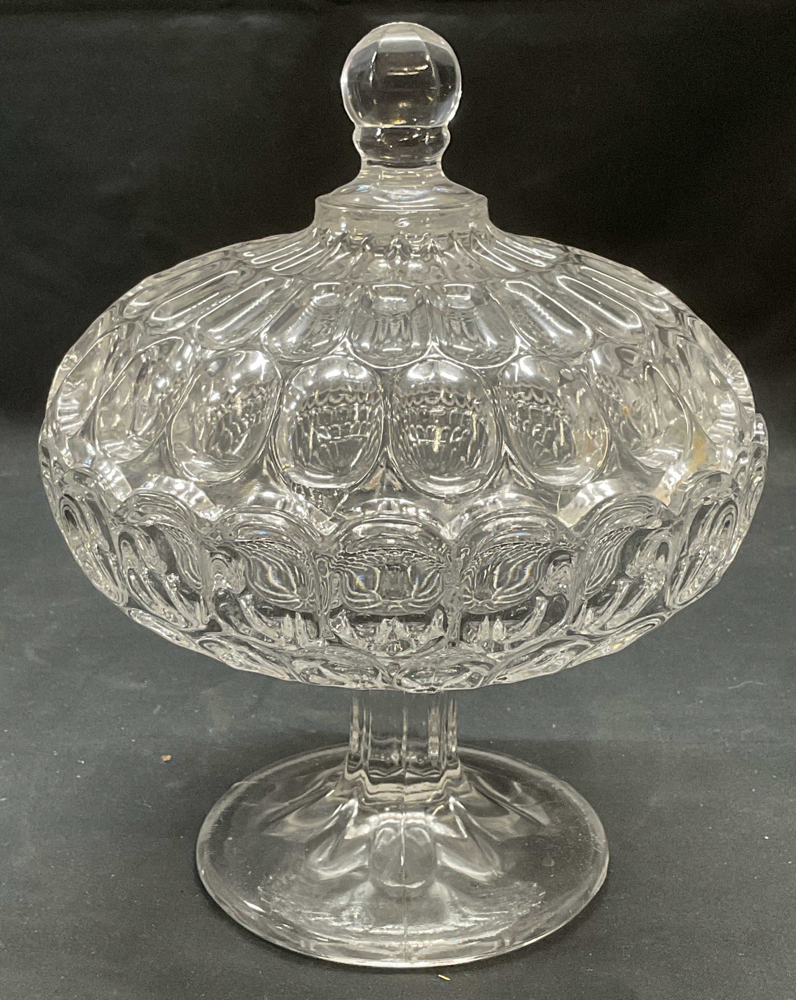 Heavy Lidded Glass Footed Candy Bowl: Footed candy bowl with lid. Raised surface with oval pattern. Thick walled glass, piece has weight. Measures approx. 6.25 x 7.5 inches, some surface wear including scratching observed. Candy bowl, nut