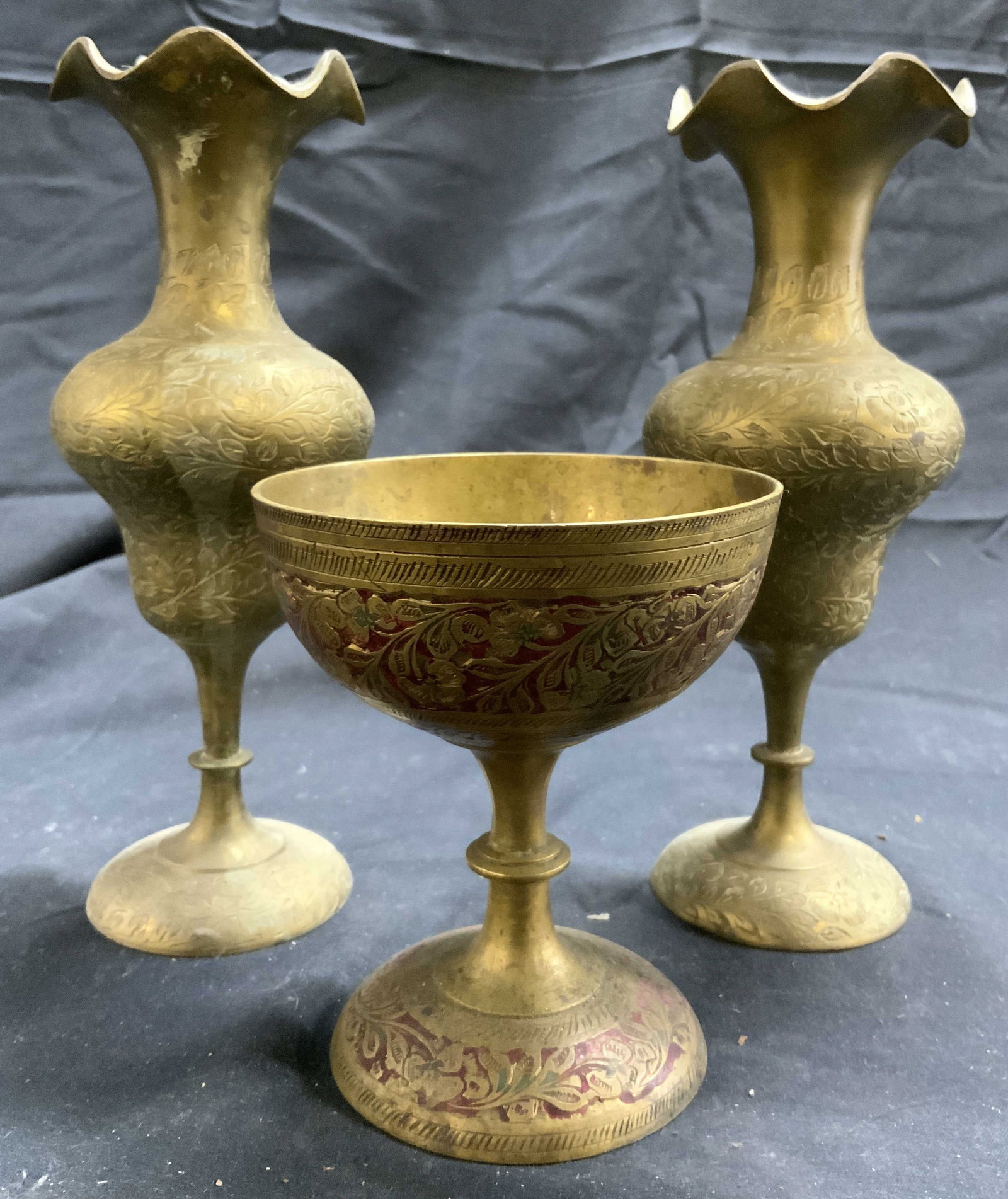 Lot 3 Vintage Brass Goblet & Vases: Lot includes 2 vases & 1 goblet. Each piece is gold toned and brass. Pieces each have intricate etched relief vine and leaf detail. Vases have handkerchief style rims. Goblet has painted red toned det