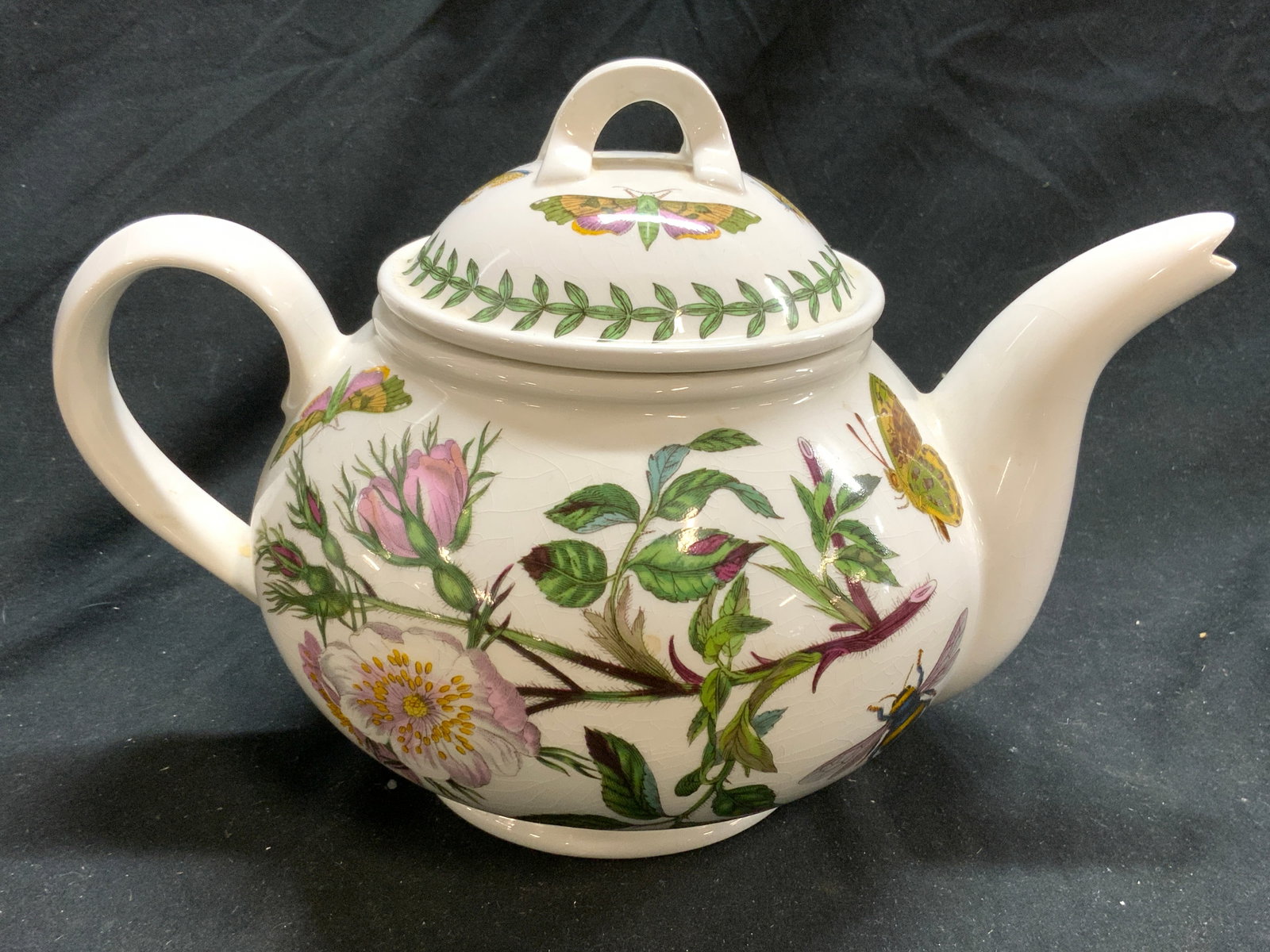 PORTMEIRION BOTANIC GARDEN Porc Teapot W Lid: Underside reads PORTMEIRION THE BOTANIC GARDEN. Teapot is vintage and porcelain. Piece has intricate multi toned floral, leaf & butterfly detail. Teapot includes lid. Piece has half heart form handle.