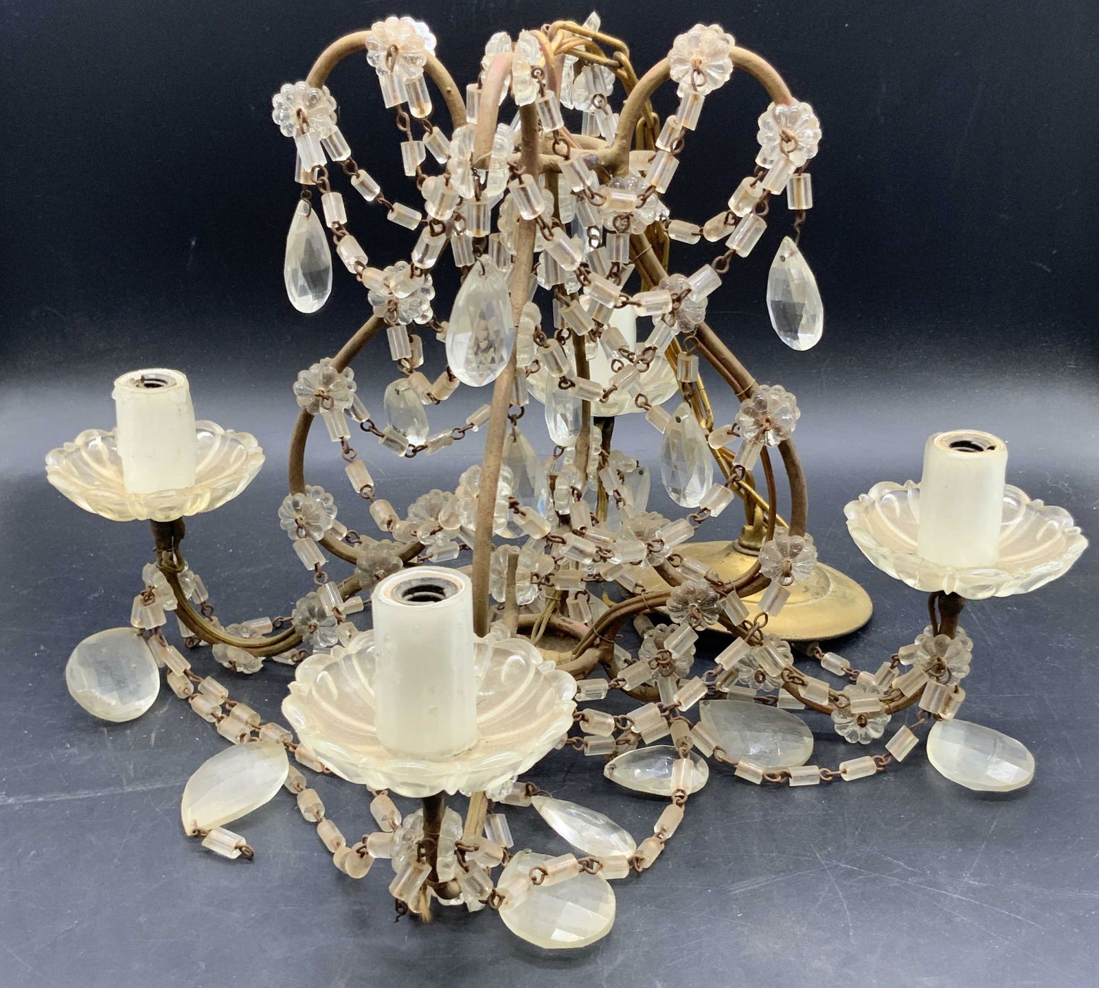 Vtg Four Light Crystal Prism Gilt Metal Chandelier: A vintage gilt four light chandelier with colorless faceted crystal prisms. Measures approx. 10H x 11.25W in. Some prisms need reattachment. Not tested for function. Some surface wear and discoloratio