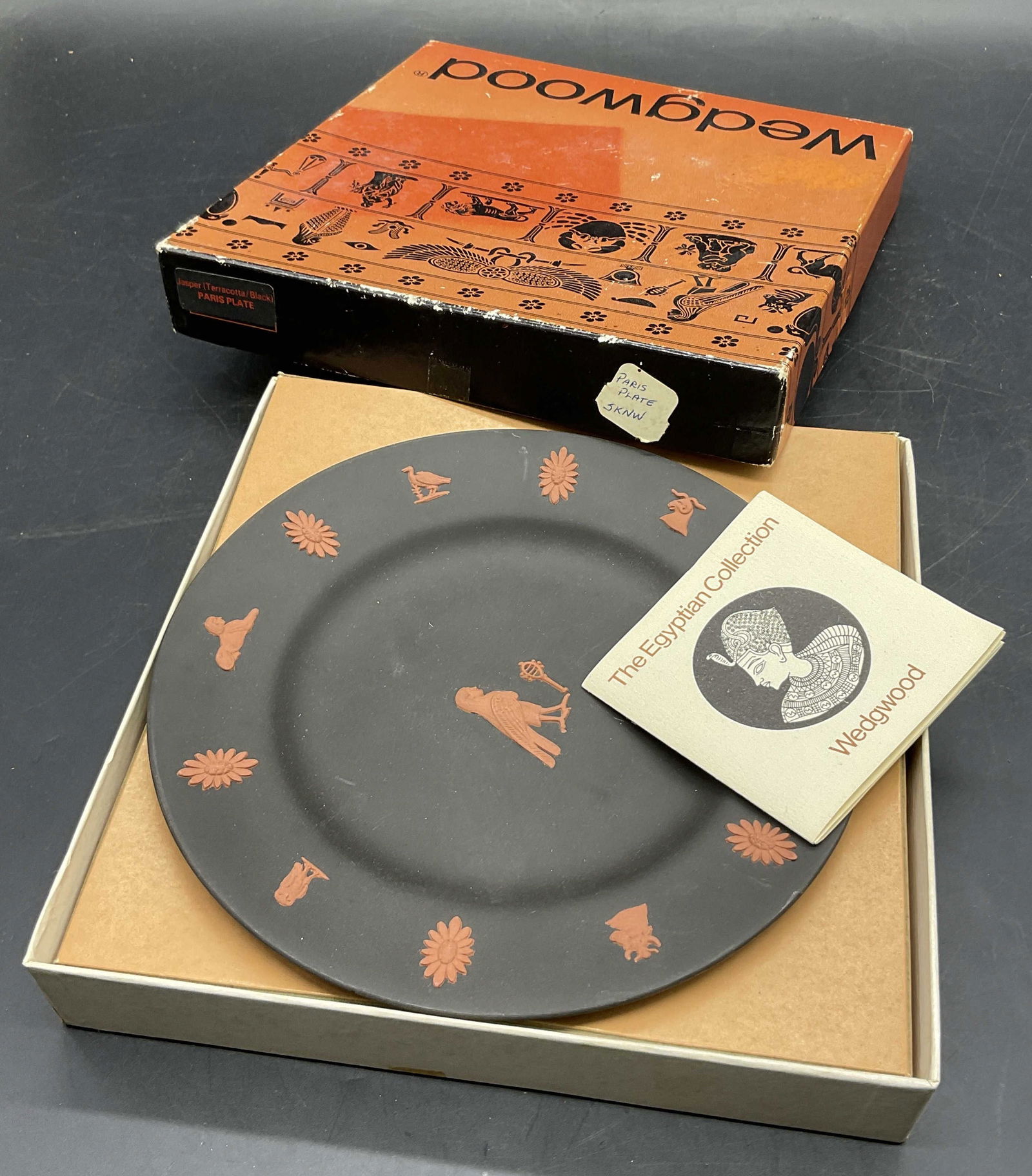 WEDGWOOD Eng Black Jasperware Plate, Original Box: A black Jasperware Wedgwood plate from their Egypt collection. Underside of plate reads WEDGWOOD, MADE IN ENGLAND. Box measures approx. 7.5L x 7.25W in. Box has losses and wear present. Surface wear t