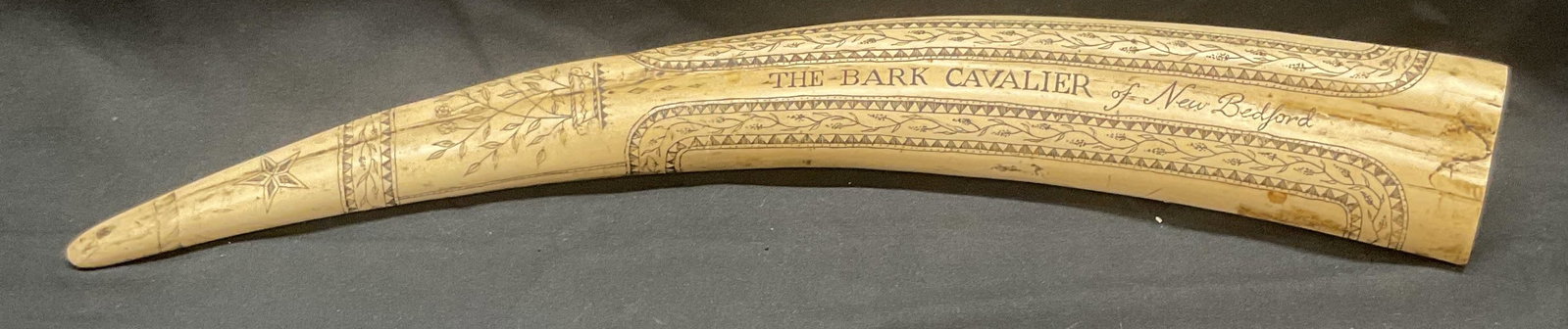 Resin Scrimshaw The Bark Cavalier New Bedford: Resin scrimshaw decorative object. Reads The Bark Cavalier of New Bedford. Design with botanical motifs landscape, and coat of arms. Measures approx. 17 inches long. Piece has weight. Surface wear inc
