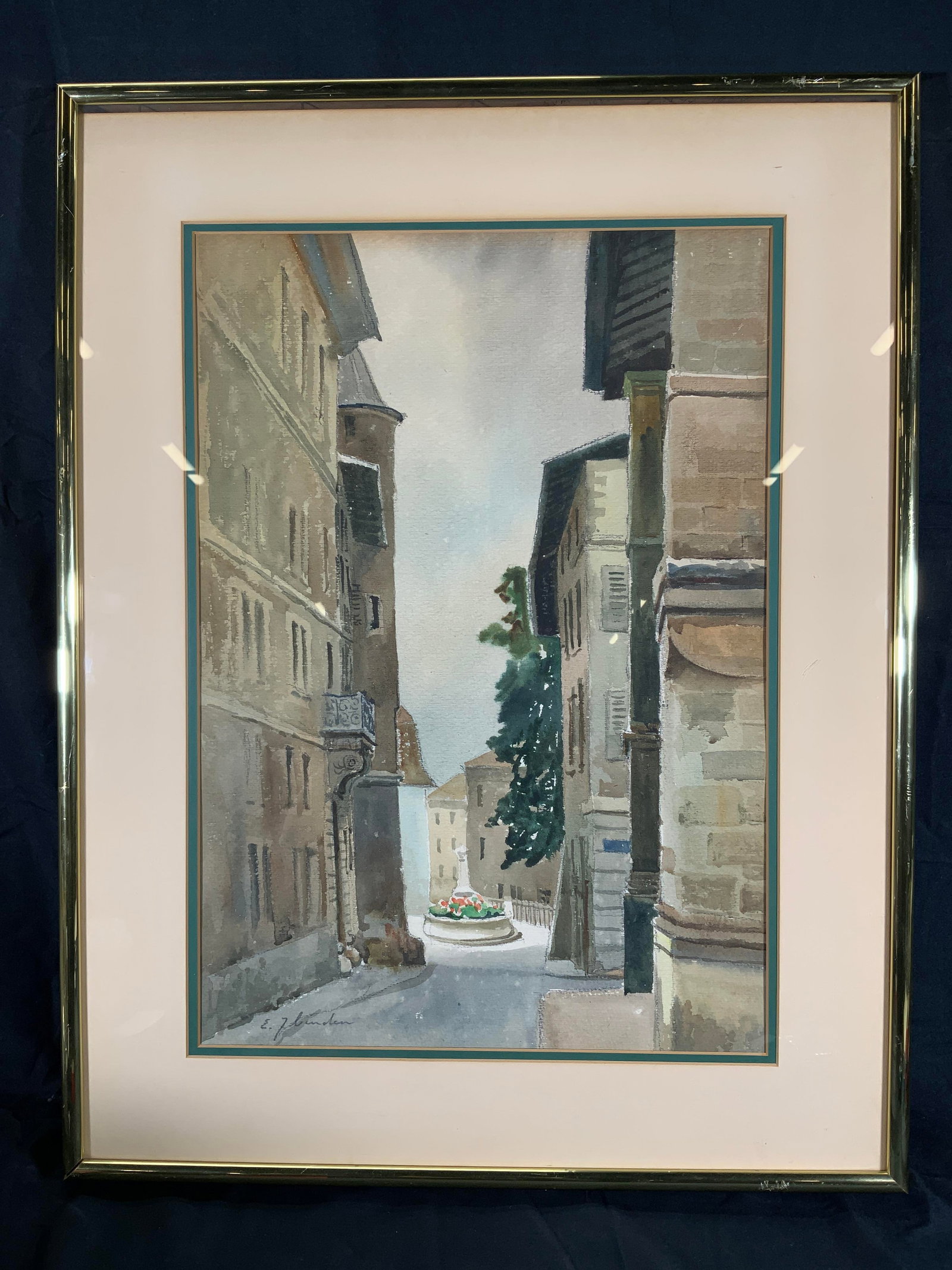 Framed & Signed Street to Town Scene Watercolor: Watercolor on paper. Signed in lower left corner. Signature illegible. Subject depicts a street leading towards an opening to a town saw her with a large center statue with flowers. Framed in a gilt w