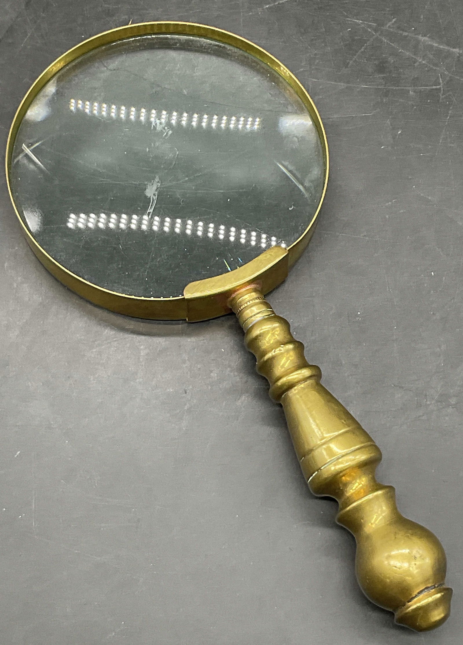 Vintage Handheld Brass Tn Metal Magnifying Glass: Vintage Handheld Brass Toned Metal Magnifying Glass. Appears to be crafted from copper with a brass toned finish. Measures approx. 8.5L x 4W in. Discoloration and surface wear present. home decor, hom