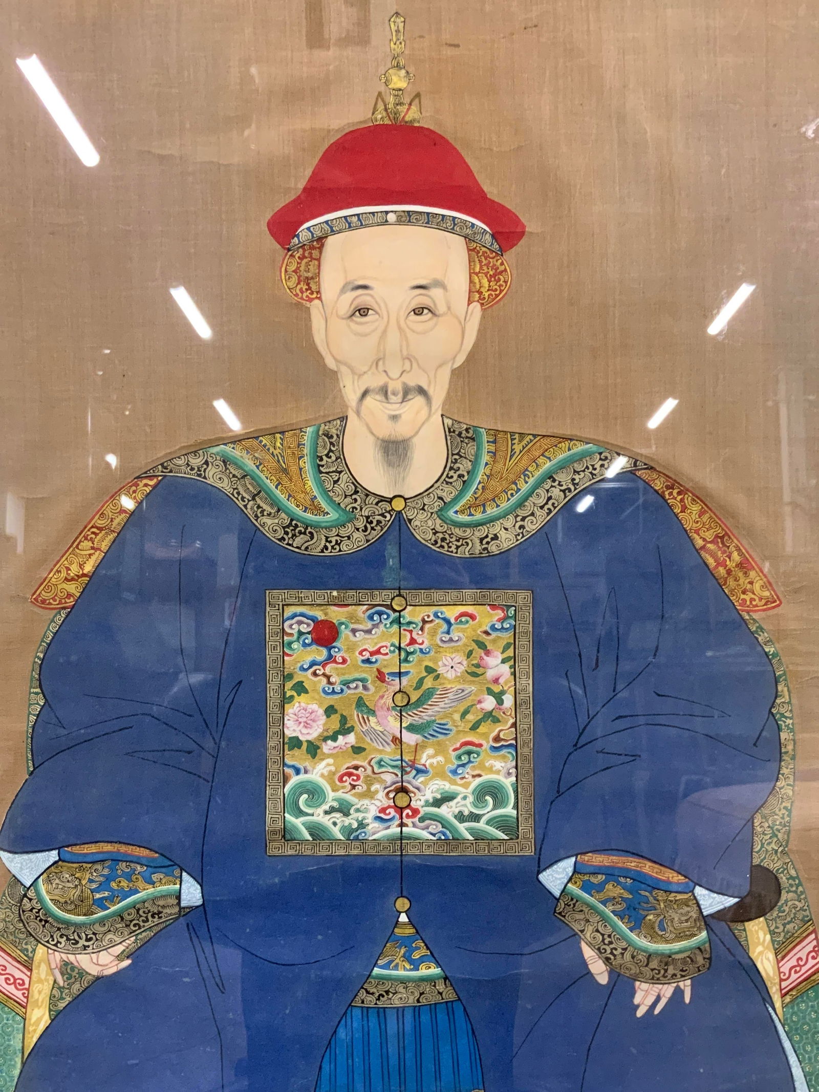 Framed Ancestor in Court Attire Portrait Painting: Painting on silk. Subject depicts a portrait of an older gentlemen wearing court attire clothing with gilt motifs of dragons and birds. Framed in a gilt wooden frame. Frame measures approx. 25 W x 46
