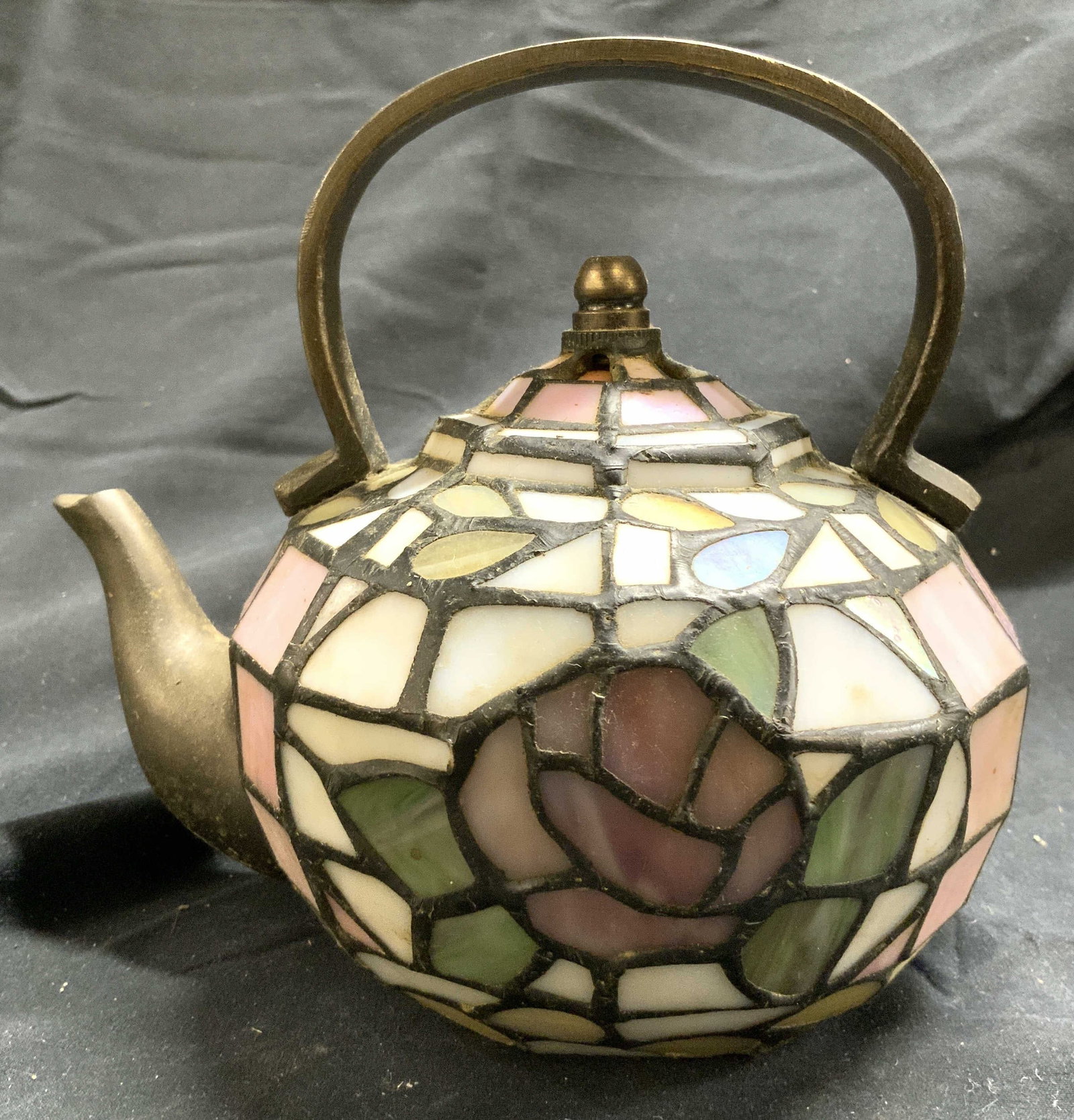 Vintage Stained Glass Teapot Shade: Shade has teapot form. Piece is crafted from stained glass. Shade has floral and leaf detail. Piece has gilt metal handle and spout. Lamp shade measures approximately 6.5 inches tall 7 inches deep 5.5