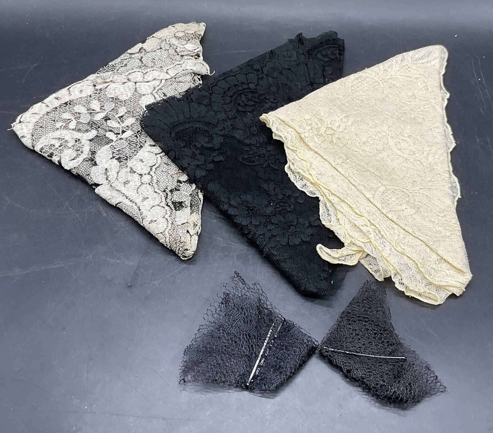 Lot 5 Vintage Lace Accessories / Wearables: Five vintage lace accessories. Pieces are various colors including black, cream, and off white hues. Cream hued piece measures approx. 39W x 19L in. Losses, holes, and surface wear present. Vintage We
