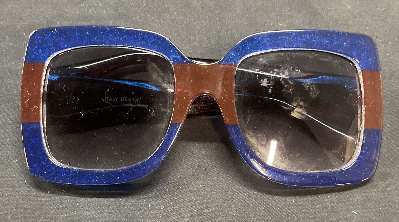 Blue Sparkle Square Sunglasses, Italy Design: Blue and brown striped sparkle acrylic square frame sunglasses. Italian design. Measures approx approx. 6 x 2.5 inches, arm approx. 5.5 inches long. Wear to frames and lenses including scratching and