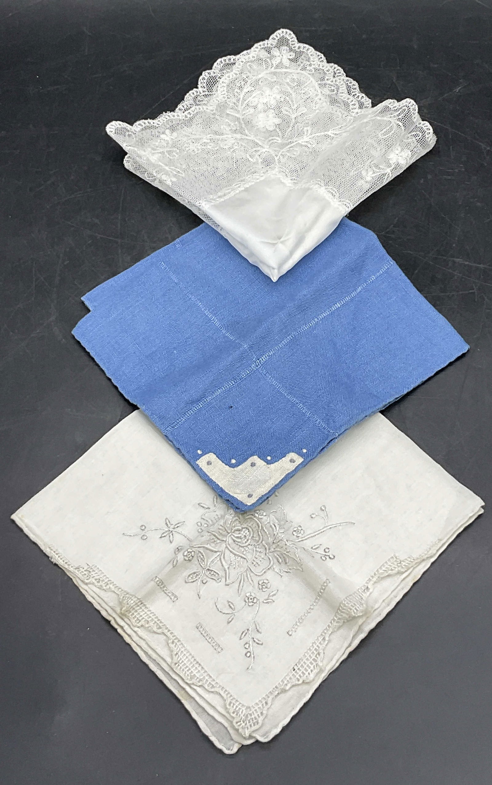 Lot 3 Vintage Handkerchiefs, White Lace Hanky +: Three vintage soft hand fabric handkerchiefs. One blue handkerchief with white embroidery and two white hued handkerchiefs featuring embroidery or lacework. Blue hanky measures approx. 10.5L x 10.5W i