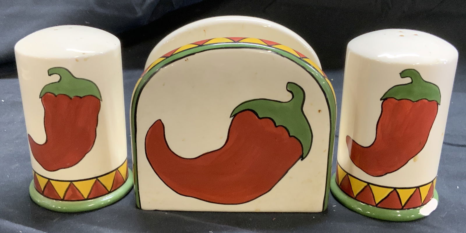 Lot 3 Porc Salt & Pepper Shakers & Napkin Holder: Tags on undersides reads CLAY ART. Lot includes salt and pepper shakers & 1 napkin holder. Each piece is porcelain. Pieces each have green, red and yellow toned detail. Each have images of peppers. Na