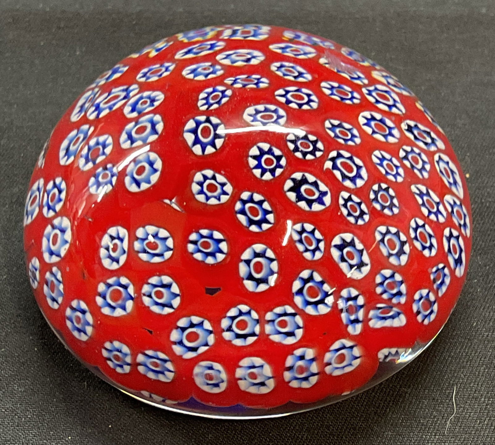 Hand Blown Art Glass Millefiori Paperweight: Hand blown art glass paperweight. Millefiori decoration in blue and red. Measures approx. 2.5 x 1.25 inches. Some surface wear including scratching observed. Art glass, art glass paperweight, floral p