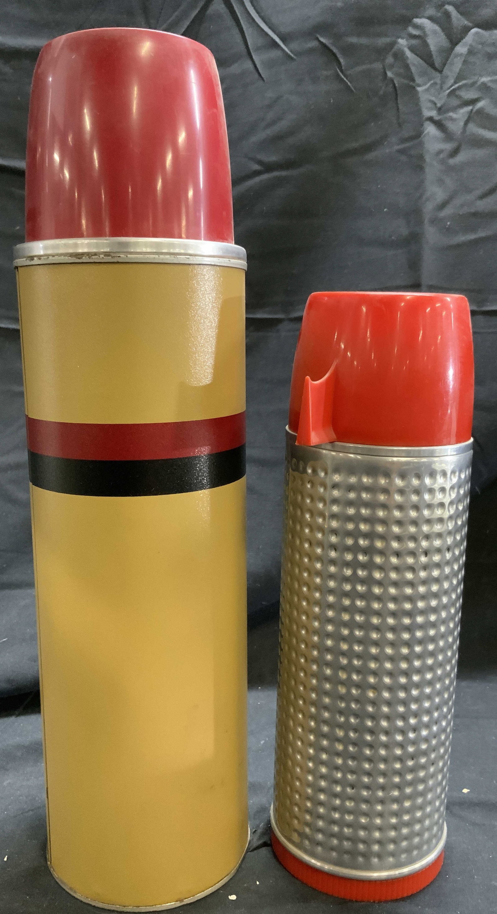 ALADDIN & THERMOS Lot 2 Vintage Thermoses: Lot includes 2 thermoses. Underside of 1 reads THERMOS, underside of the other reads ALADDINS THERMO KING THERMOS BOTTLE. Lot includes 1 silver toned metal thermos with red cap, & 1 beige red and blac