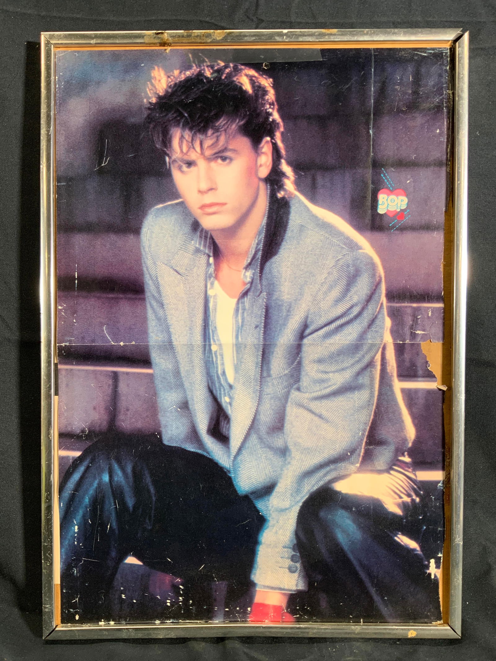 Framed John Taylor Great Faces Magazine Poster: Lithograph of a Photo. Subject appears to be John Taylor from Duran Duran posing in a photo shoot with a blazer on, appears to be from a 1985 Tiger Beat Star Great Faces magazine. Framed in a silver t