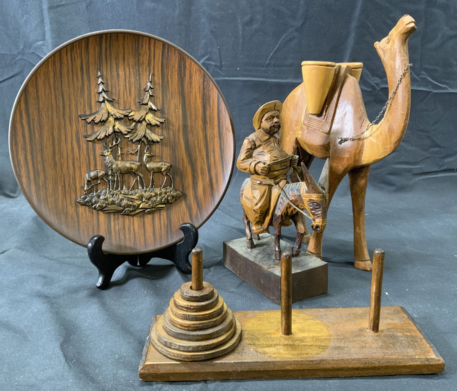 Lot 4 Wooden Home & Table Accessories: 4 wooden home accessories. Wooden camel figural. Camel has a saddle with two vases. Small chain is affixed to camels neck. Camel measures approx. 7 W x 9.5 H x 3 D in. Man riding donkey figural on bas