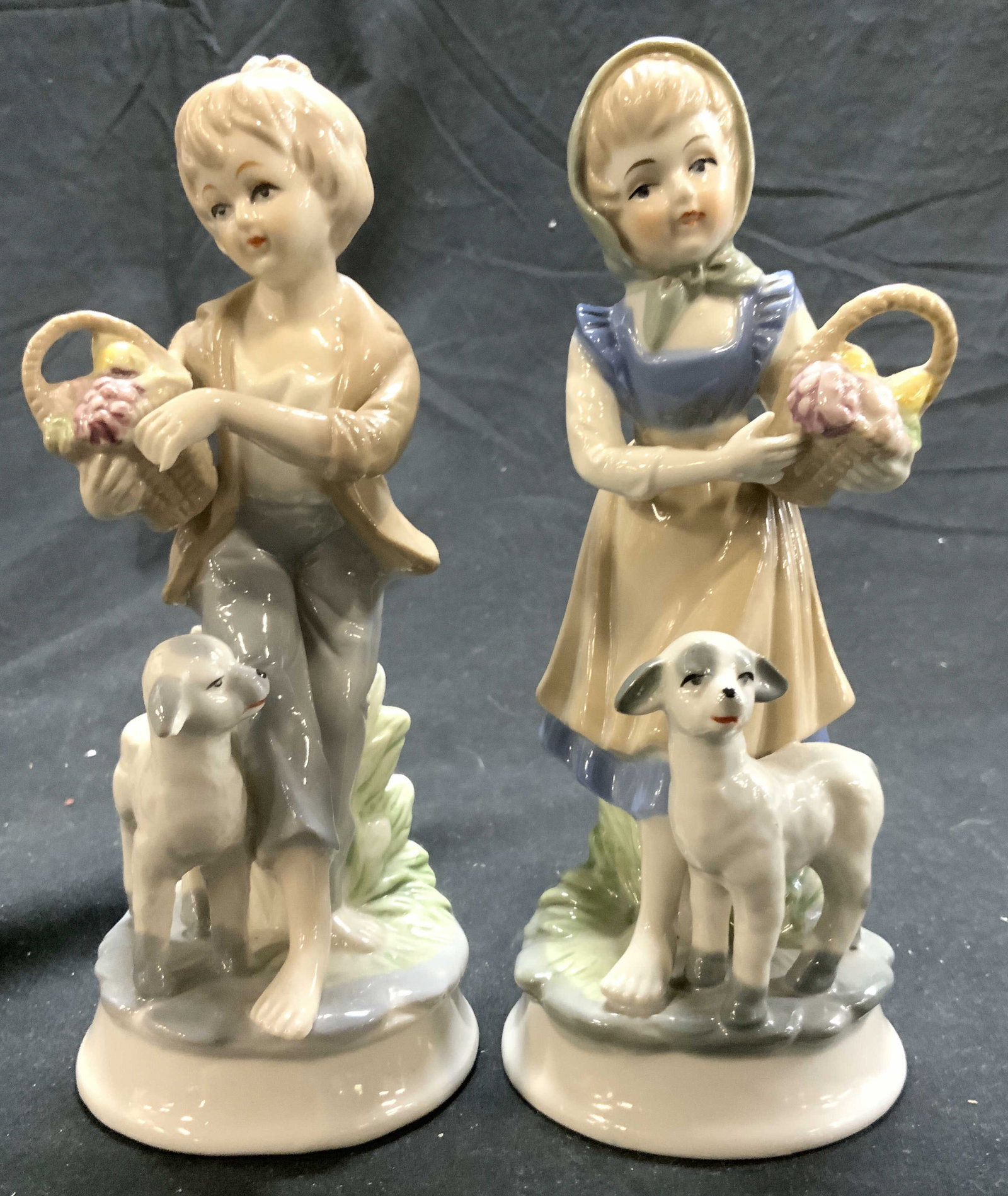 Lot 2 Vintage Porcelain Boy & Girl Figurals: Lot includes 1 girl figure holding basket with lamb, & 1 boy figure holding basket with lamb. Each piece is vintage and porcelain. Each piece has circular form bases. Each measures approximately 7 inc