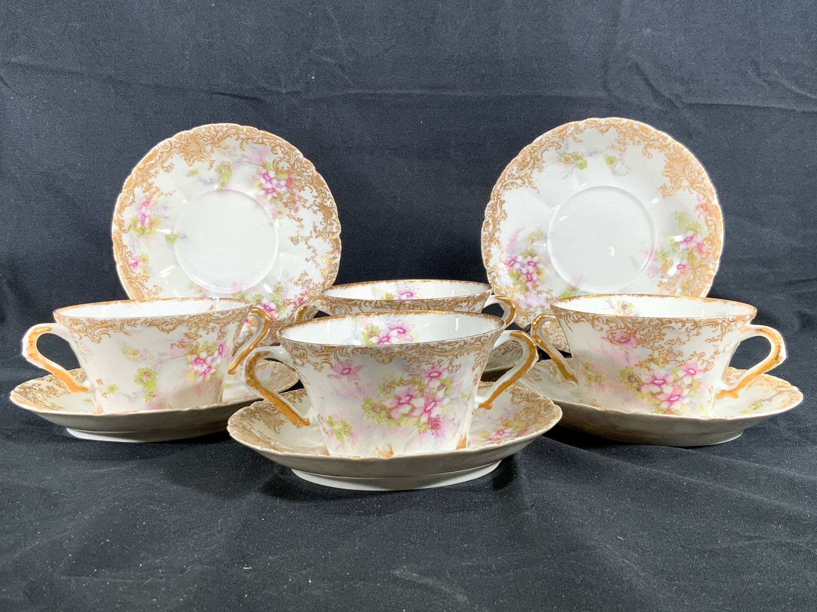 Theo. Haviland Limoges Tea Cup & Saucers Set: 4 porcelain tea cups and 6 saucers. Undersides read Porcelaine, Theo Haviland, Limoges France, Higgins & Seiter. Tea cups have floral motifs on interior and exterior of cup and scrolling floral gilt a