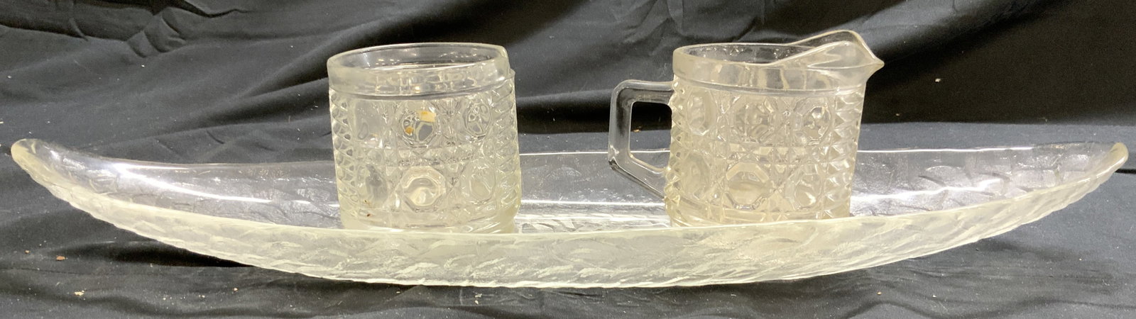 Lot 3 Art Glass Creamer Sugar & Serving Dish: Lot includes 1 serving dishes, 1 creamer dish & 1 sugar dish. Each piece is glass. Creamer and sugar dishes have geometric relief detail. Serving dish has elongated form. Serving dish measures approxi