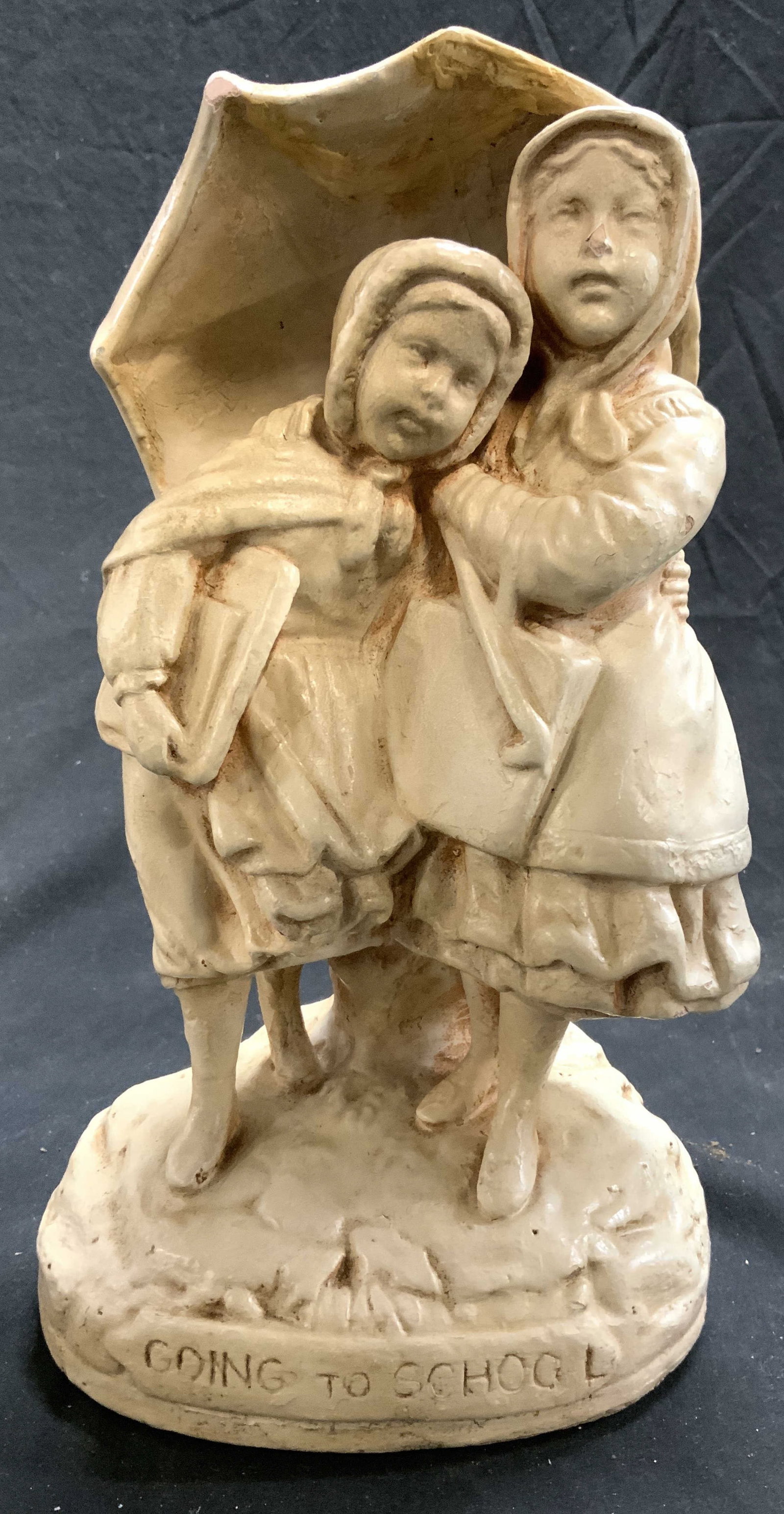 GOING TO SCHOOL Vntg Ceramic Fig Of Children: Base is inscribed GOING TO SCHOOL. Figure is vintage. Piece is cream toned and appears to be ceramic. Figure depicts 2 children wearing coats, walking with an umbrella. Piece measures approximately 11