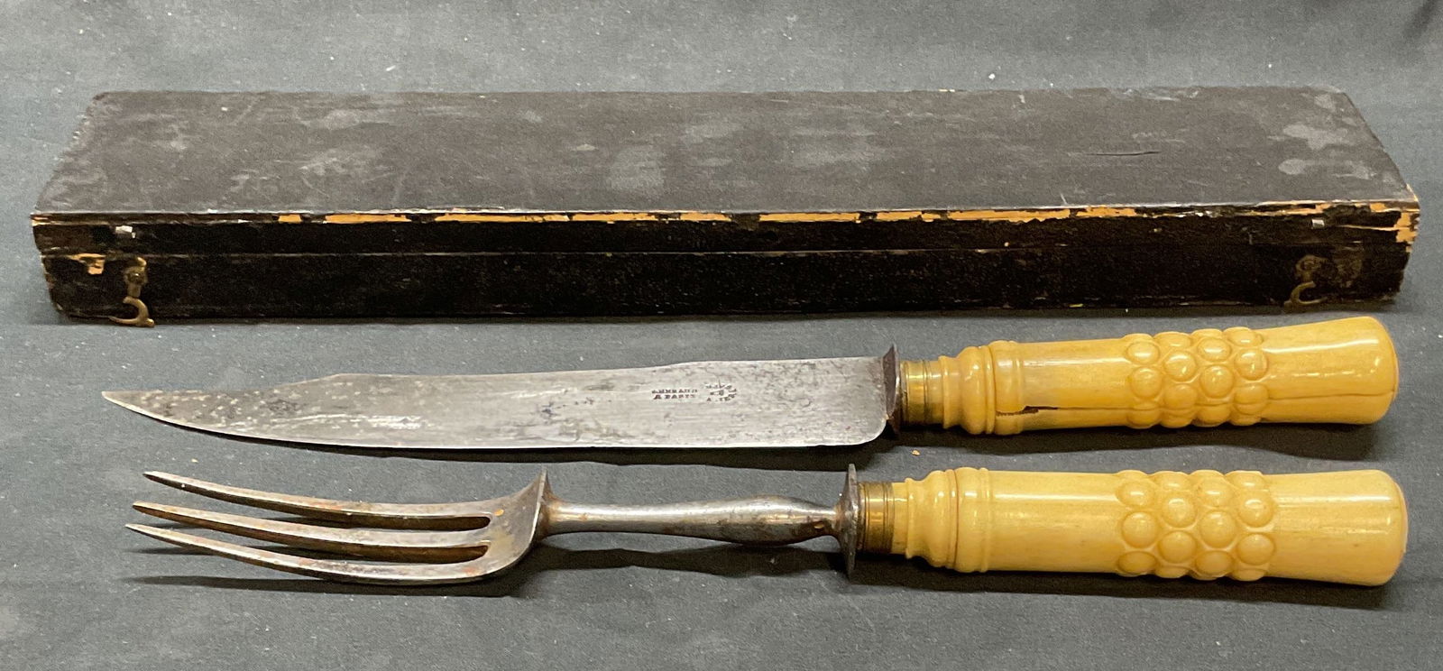 Vintage Signed Faux Bone Knife & Fork, France: Vintage signed carving fork and knife with faux bone handles. Signed on knife blade, partially legible, reads Paris. Larger piece measures approx. 12 inches long. Includes box, signifying wear to case