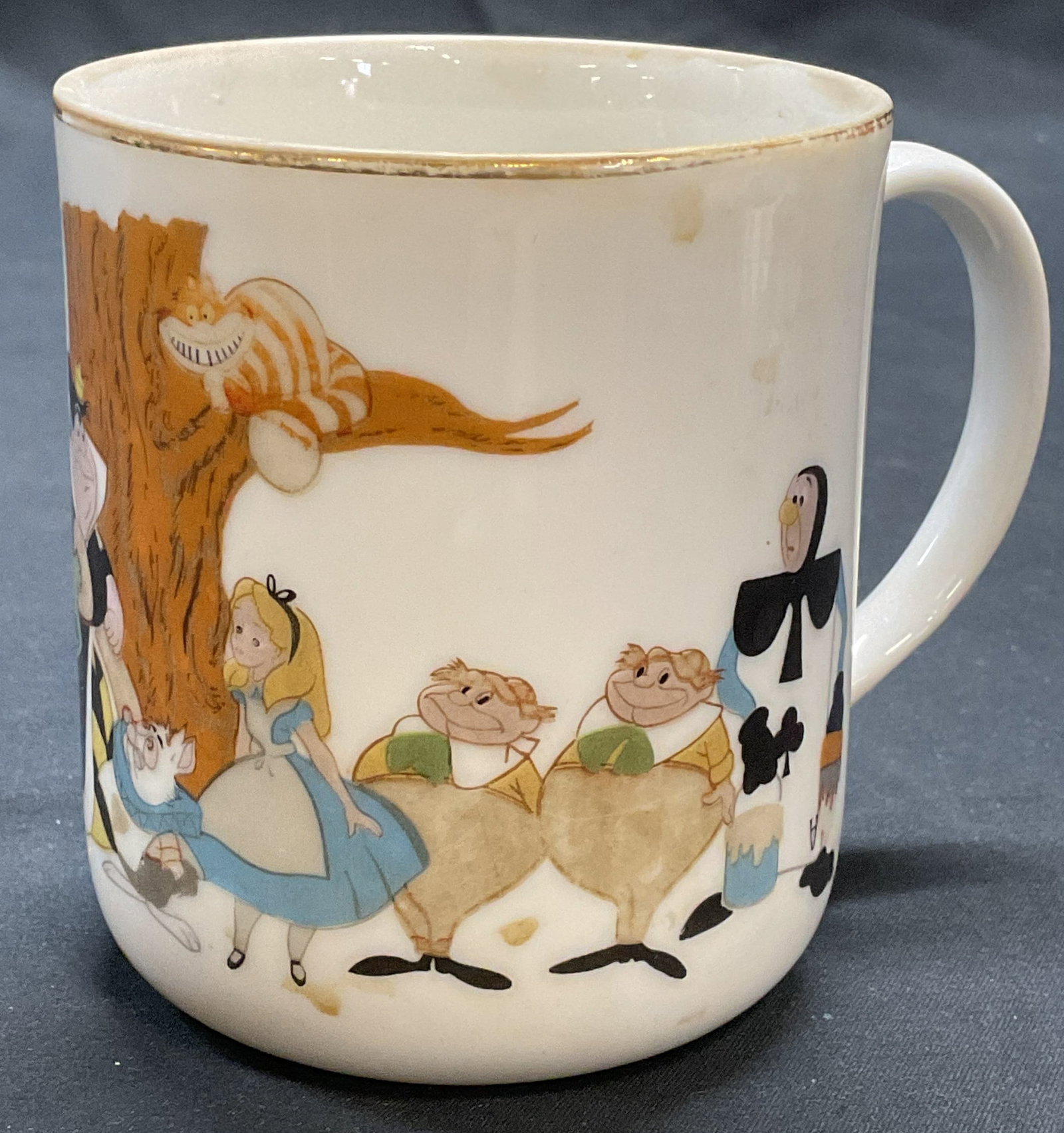 Vntg Walt Disney Alice in Wonderland Porc Mug: Vintage Walt Disney Productions Alice In Wonderland motif porcelain mug with gilt decoration. Signed on underside. Measures approx. 3 x 3.5 inches. Some surface wear including loss to paint observed. 
