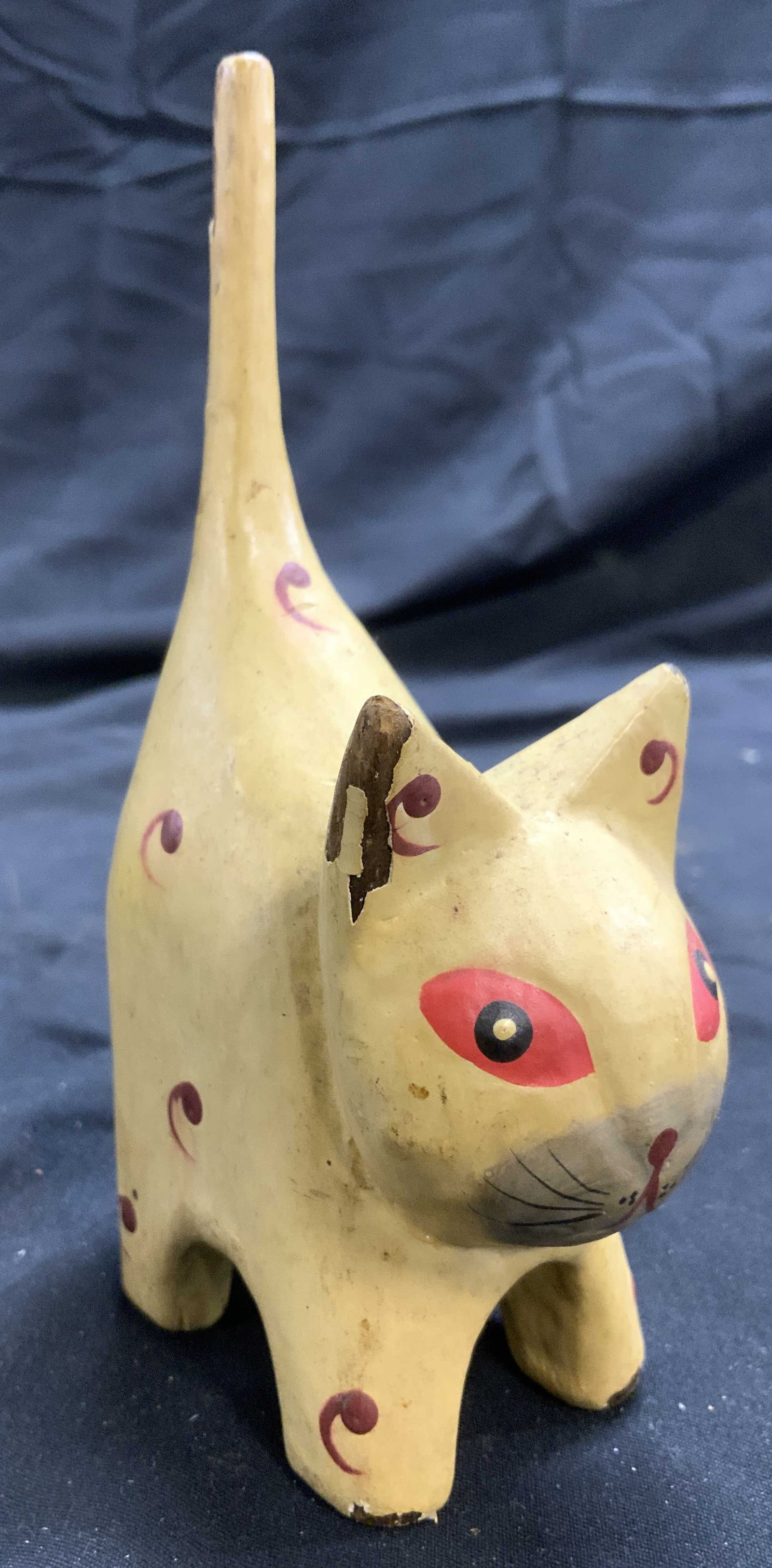 Hand Crafted Carved Wooden Cat Figural: Cat figure is hand crafted. Piece appears to be a lightweight wood material. Cat figure is yellow with red toned pattern detail & red toned eyes. Piece has facial detail. Cat figure measures approxima