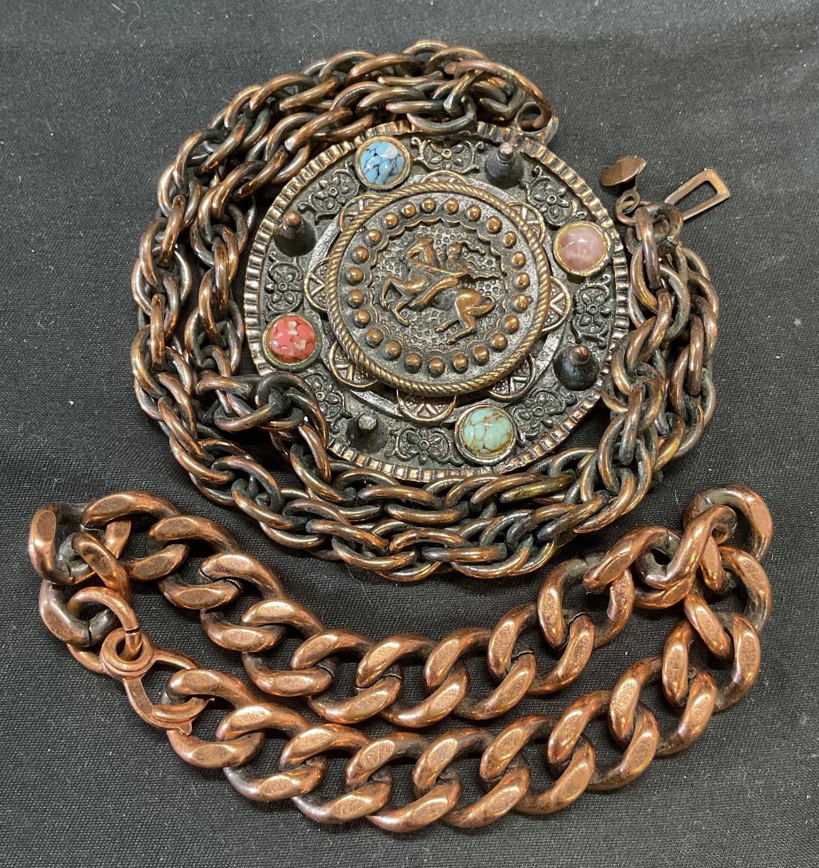 Lot 2 Copper Patina Pendant Necklace +: Copper patina pendant necklace with colored faux stone decoration and horse and figural motifs. Drop length approx. 8 inches, pendant approx. 2.25 inches wide. Heavy copper chain bracelet. Measures ap