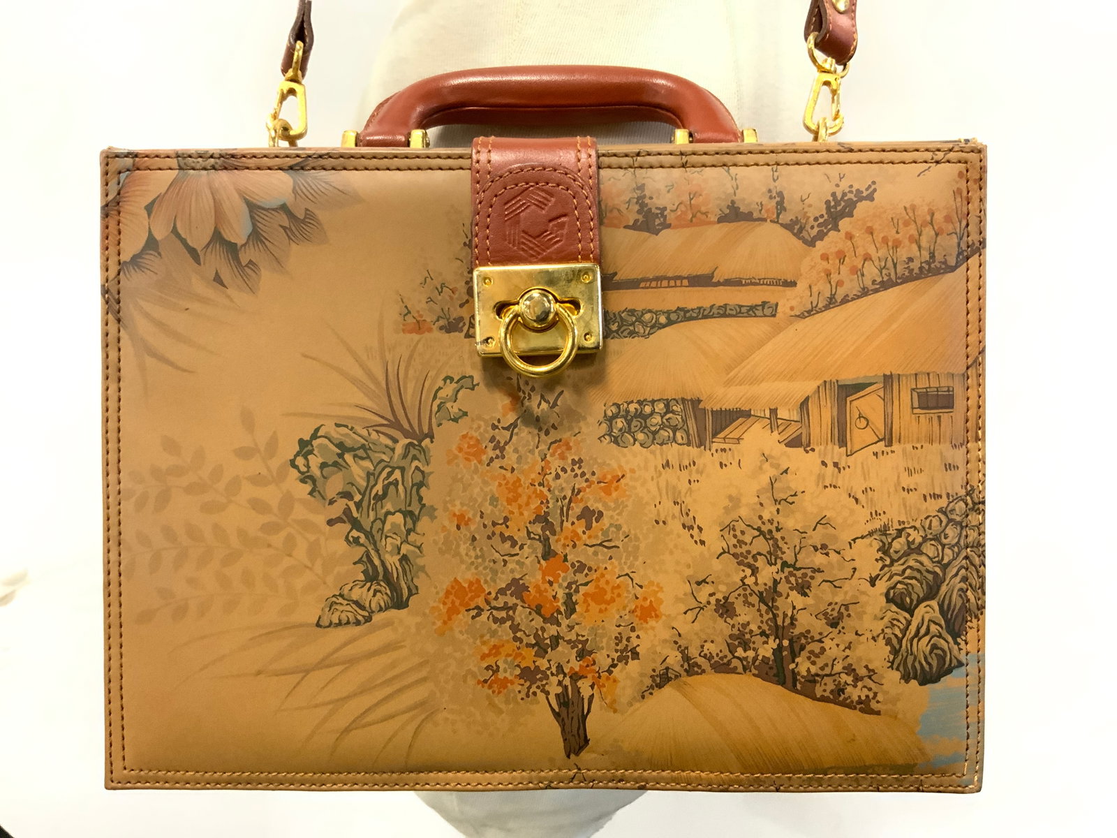 DESIGN BY B&K Leather Womens Suitcase Handbag: Interior is inscribed DESIGN BY B&K. Handbag has suitcase form. Piece is tan toned, appears to be leather. Handbag has multi toned floral, leaf & landscape detail. Handbag has handle & strap. Interior