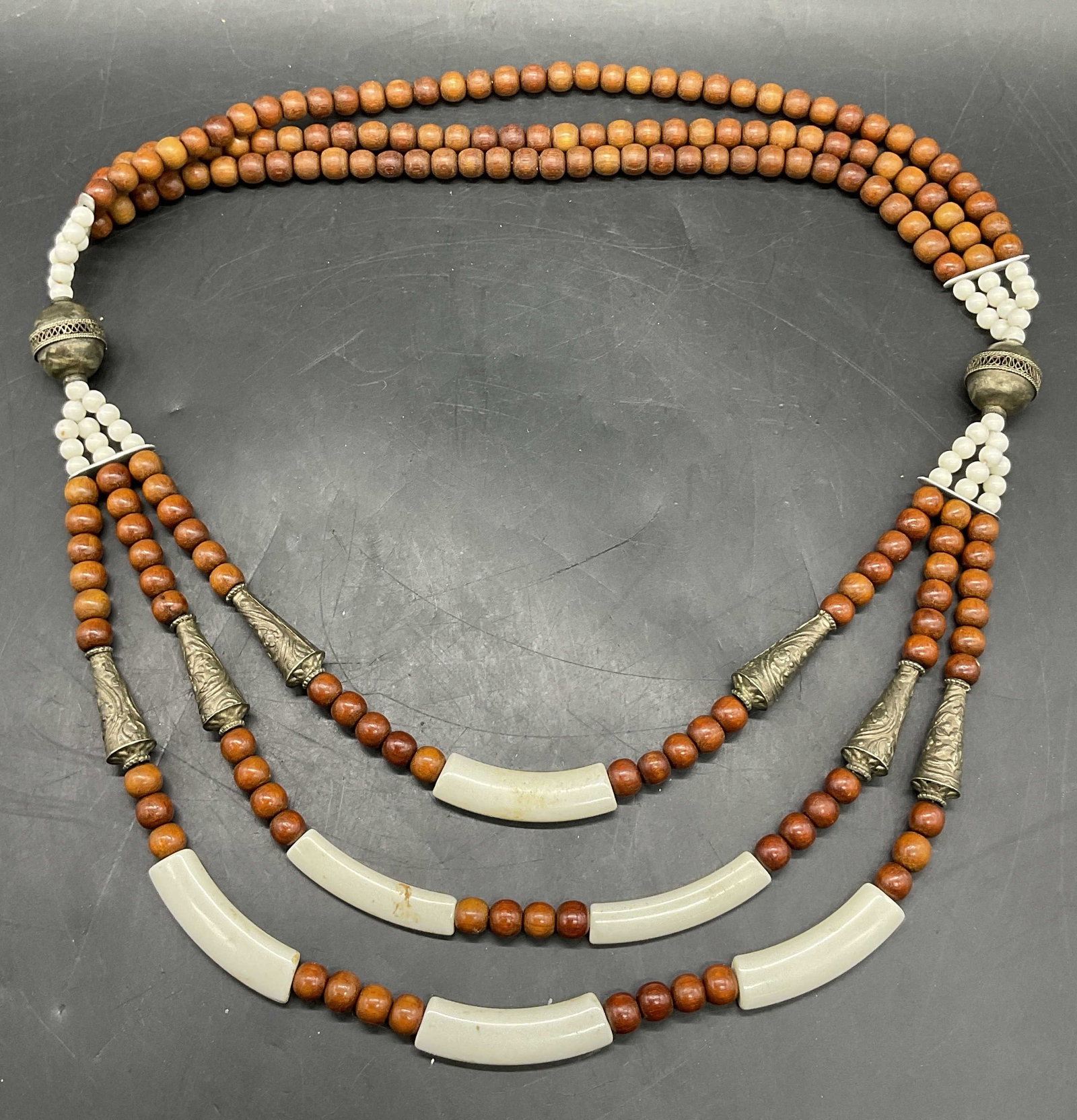 Vintage Tibetan Style Wood & Metal Beaded Necklace: A vintage Tibetan style necklace crafted from brown wooden beads, glass white beads, and silver tone metal conical & round beads. Drop length approx. 11 inches. Some losses to finish, discoloration, a