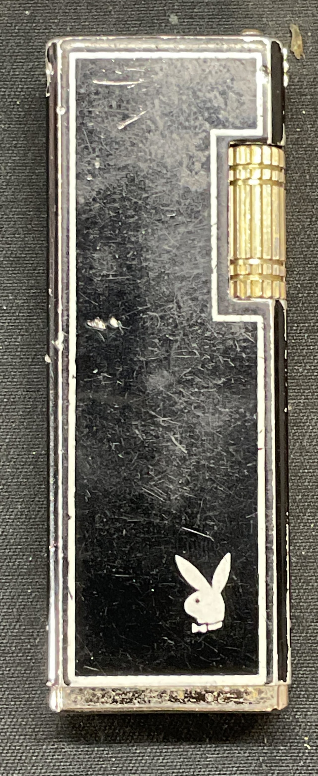 Vintage Playboy Bunny Enamel Lighter: Vintage Playboy bunny lighter. Black and white enamel over metal. Measures approx. 2.5 x .5 x 7/8 inches. Not tested for function. Surface wear including scratching and loss to enamel observed. Playbo