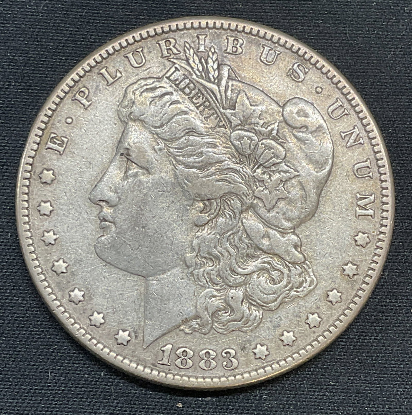 Antique 1883 Liberty Morgan Silver Dollar: Antique 1883 Morgan silver dollar with raised Liberty and coat of arms motifs. Coin measures approx. 1.5 inches wide. Total weight 26.3 grams. Some surface wear including scratching and patina observe