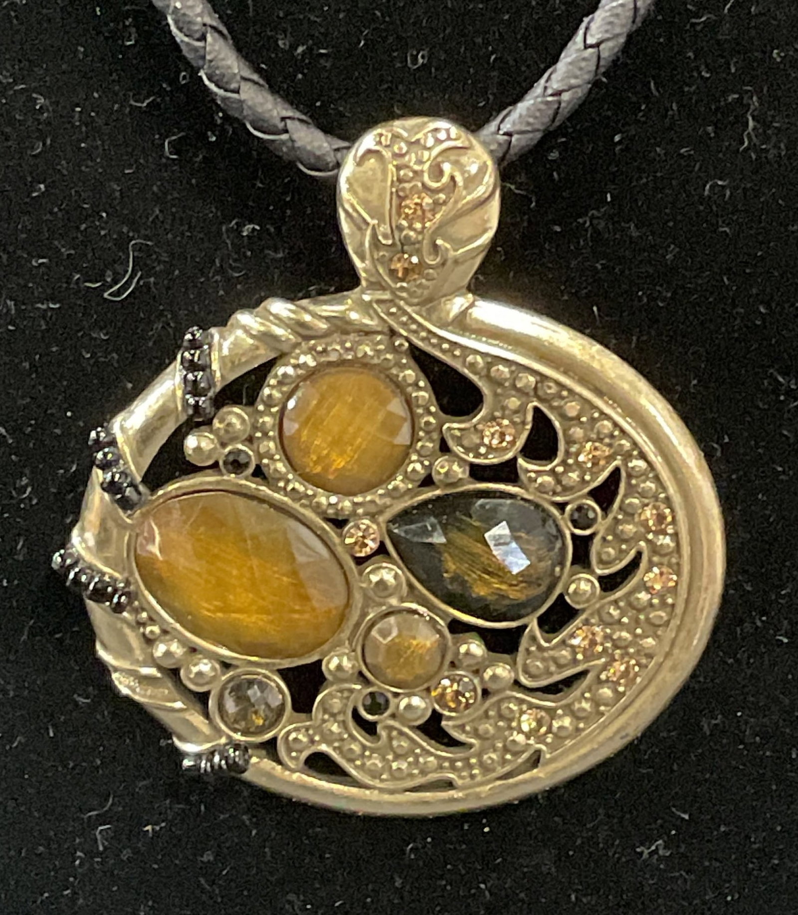 Lia Sophia Citrine Crystal Pendant Necklace: Lia Sophia gold tone faux citrine crystal pendant necklace with braided black cord. Signed on hang tag. Drop length approx. 9 inches. Pendant measures approx. 2 x 2 inches. Some surface wear including