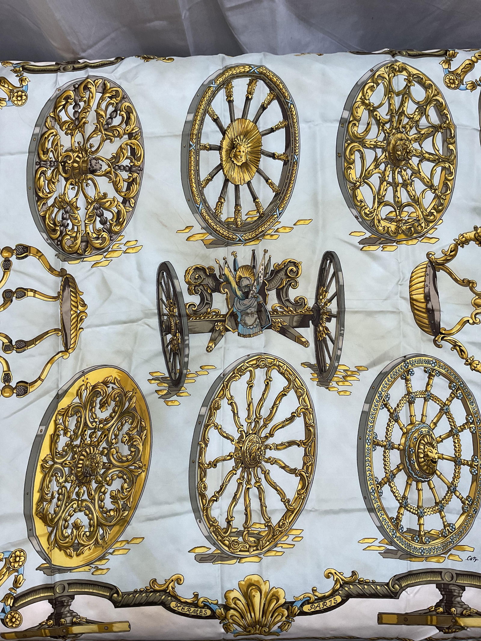 Hermes Roues De Canon Silk Scarf, Caty, France: Hermes Roues de Canon silk scarf designed by Caty Latham. Canon pattern in blue, gold, and white. Hand rolled edges, made in France. Signed at lower center, artist name at lower right. Measures approx