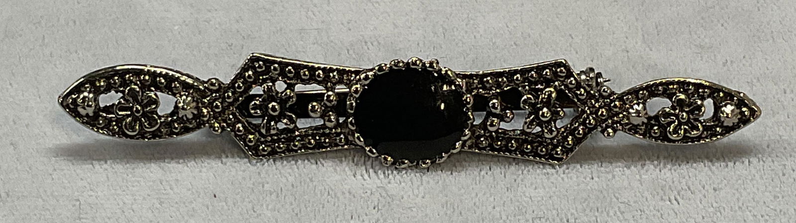 Vintage Silver Tone Floral Brooch: Vintage silver tone brooch with floral motif and black lucite cabochon. Hinge pin on underside. Measures approx. 2 inches long. Some surface wear including scratching observed. Jewelry, estate jewelry