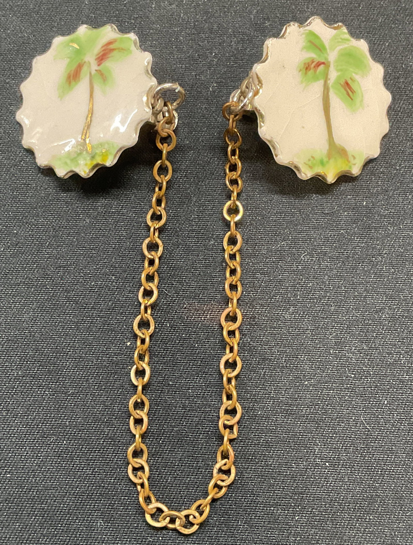 Vintage Hand Painted Palm Tree Sweater Dress Clips: Vintage double sweater or dress clips. Gold tone chain with white hand painted palm tree motif clips. Clips measure approx. 1 inch wide, chain approx. 5.75 inches long. Some surface wear including scr