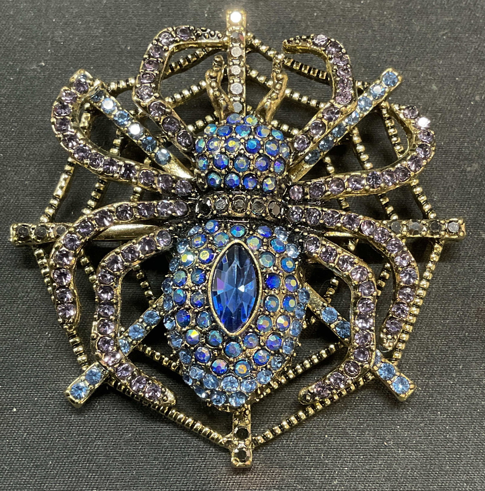 Xl Gold Tone Crystal Spider & Web Brooch 2.75 In: Gold tone spider and web motif brooch with purple and blue crystal decoration. Hinge pin on underside. Measures approx. 2.75 inches wide. Piece has weight. Some surface wear including scratching obser