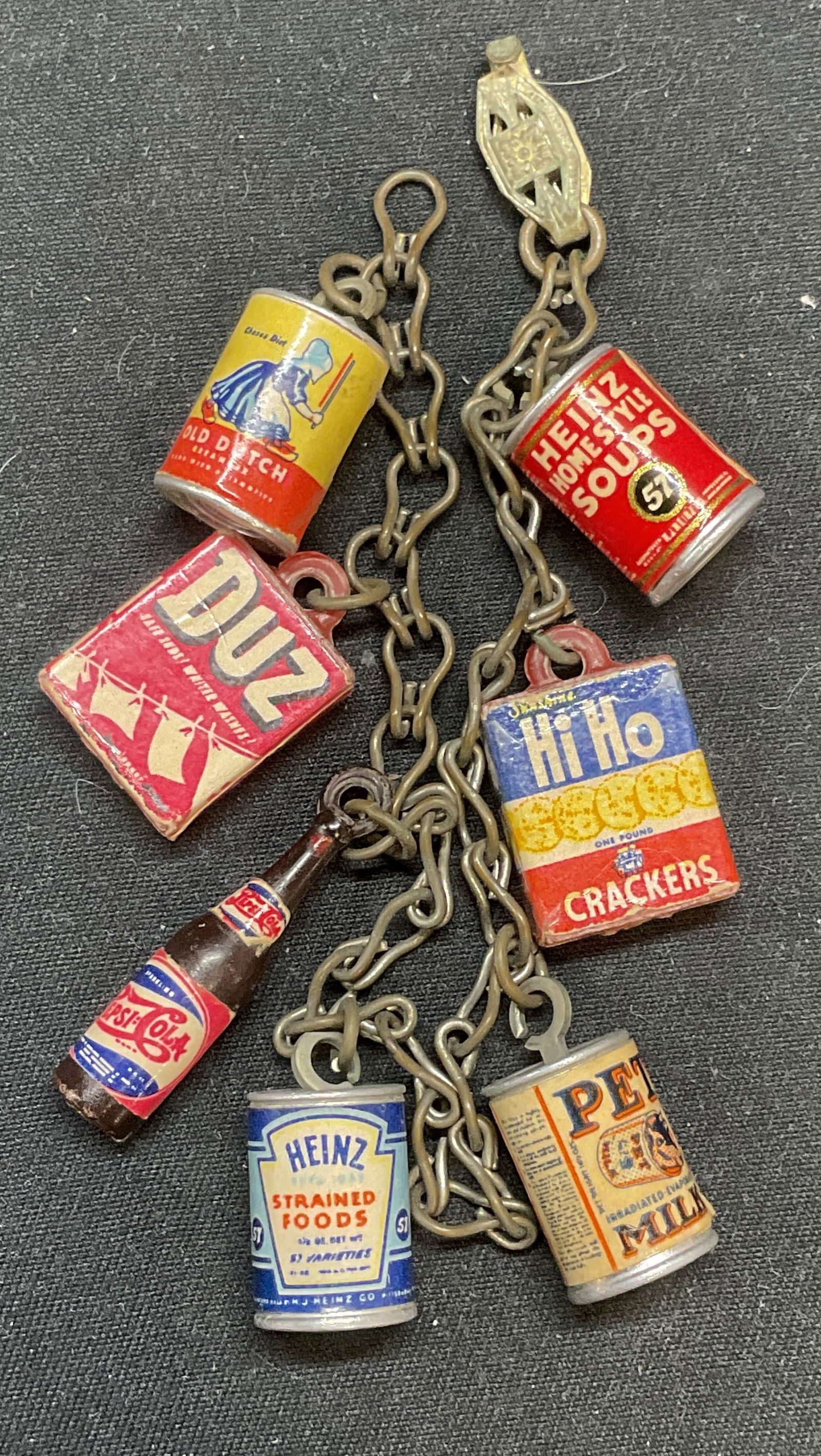 Vintage grocery Pantry Motif Charm Bracelet: Vintage charm bracelet with miniature grocery/pantry motif charms. Old Dutch, Duz, Pepsi Cola, Heinz, Pet Milk, and Hi Ho charms. Measures approx. 7 inches long. Some surface wear including scratching