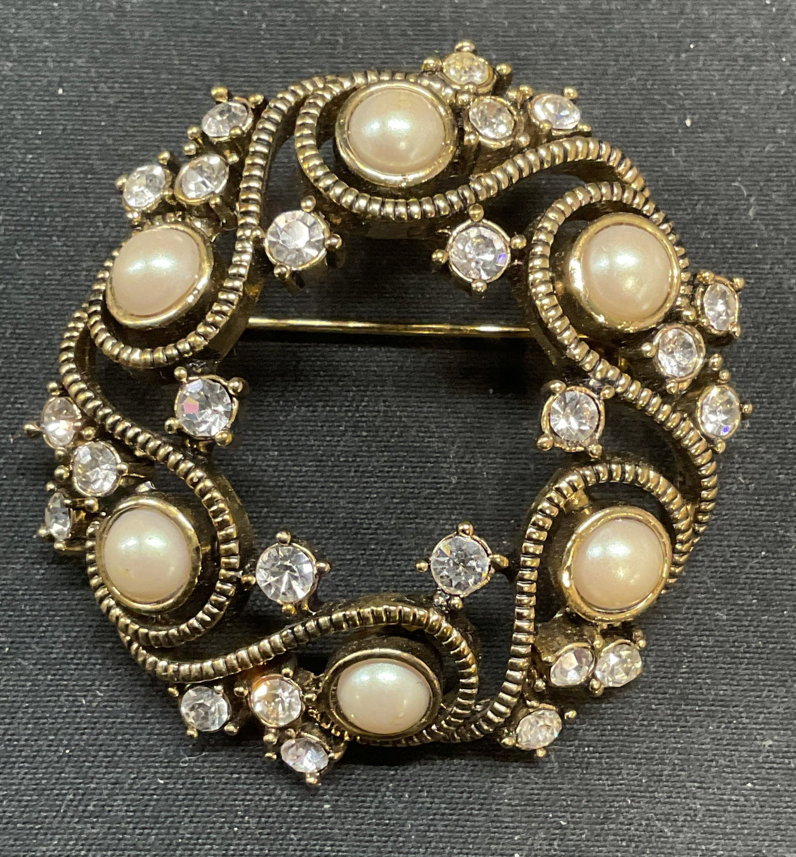 Vintage Monet Gold Tn Faux Pearl Crystal Brooch: Vintage Monet gold tone open circle brooch with faux pearl and colorless crystal decoration. Signed on underside. Hinge pin on underside. Measures approx. 1.75 inches wide. Some surface wear including