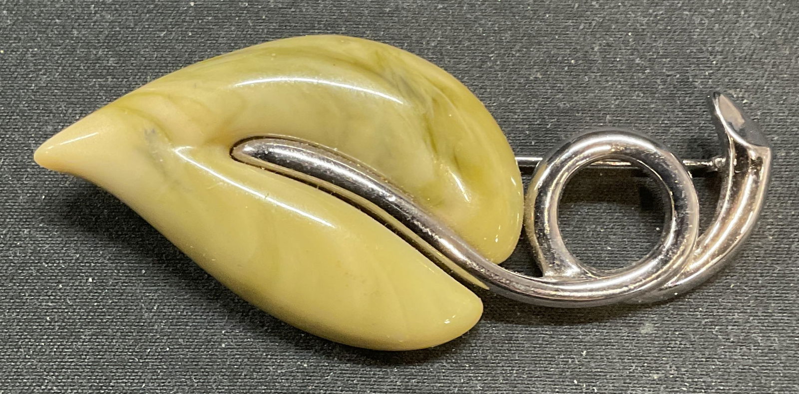 Lauren Conrad Green Lucite Leaf Brooch: Lauren Conrad silver and green lucite leaf motif brooch. Signed LC on underside. Hinge pin on underside. Measures approx. 3 x 1.25 inches. Some surface wear including scratching observed. Jewelry, est