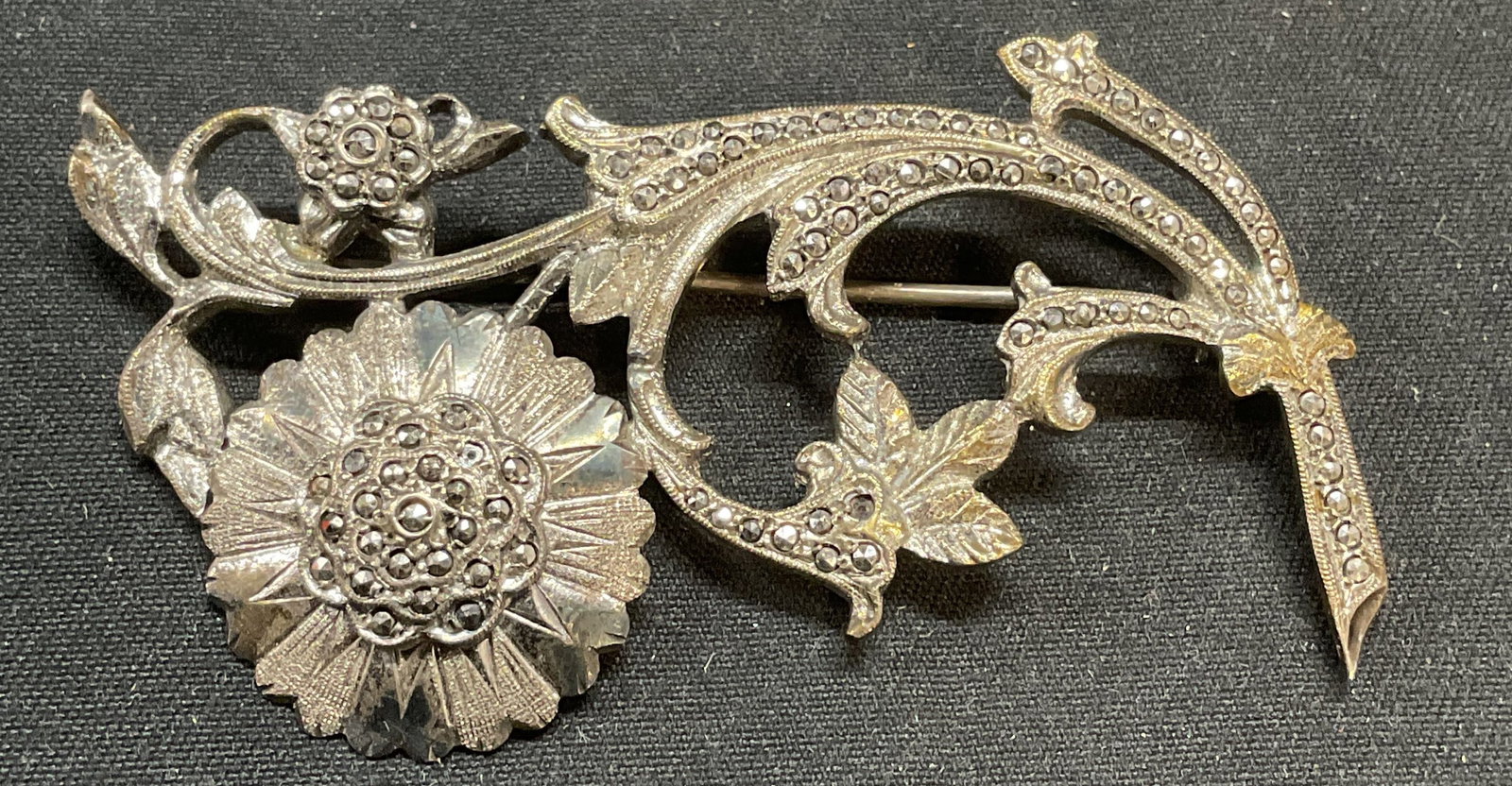 Vintage Sterling Silver & Marcasite Flower Brooch: Vintage sterling silver and marcasite decorated flower np motif brooch. Hinge pin on underside. Marked sterling. Measures approx. 2.25 x 1.25 inches. Total weight 13.5 grams. Some surface wear includi