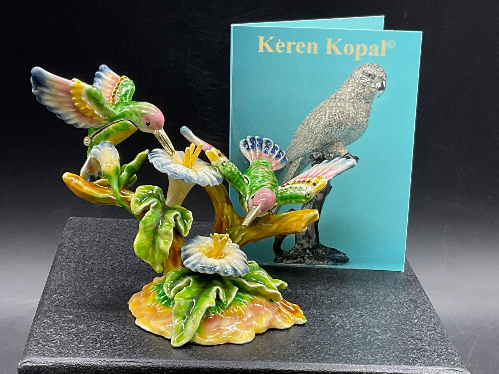 KEREN KOPAL Humming Birds Trinket Box W/ Bx: Keren Kopal humming birds on flower trinket box. Enamel and crystal decoration. Signed KEREN KOPAL. Measures approx. 3H x 4.25W inches. Includes presentation box with lining and fitted compartment. Co