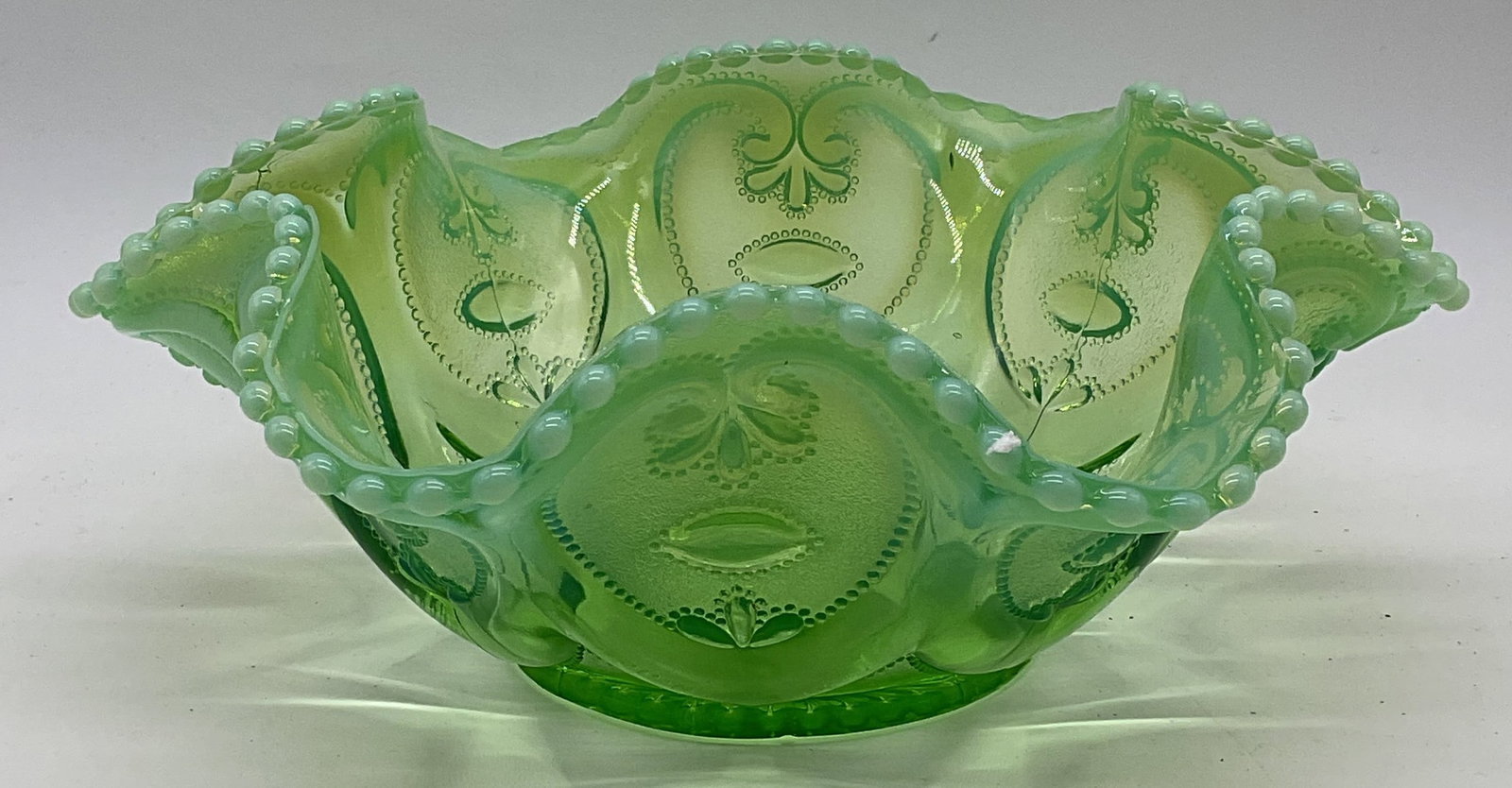 Vintage Opalescent Green Jeweled Heart Glass Bowl: Vintage opalescent green glass bowl with jeweled heart pattern. Handkerchief rim. Style of Dugan Glass Co. measures approx. 10 x 4 inches. Some surface wear including scratching and hairline crack obs