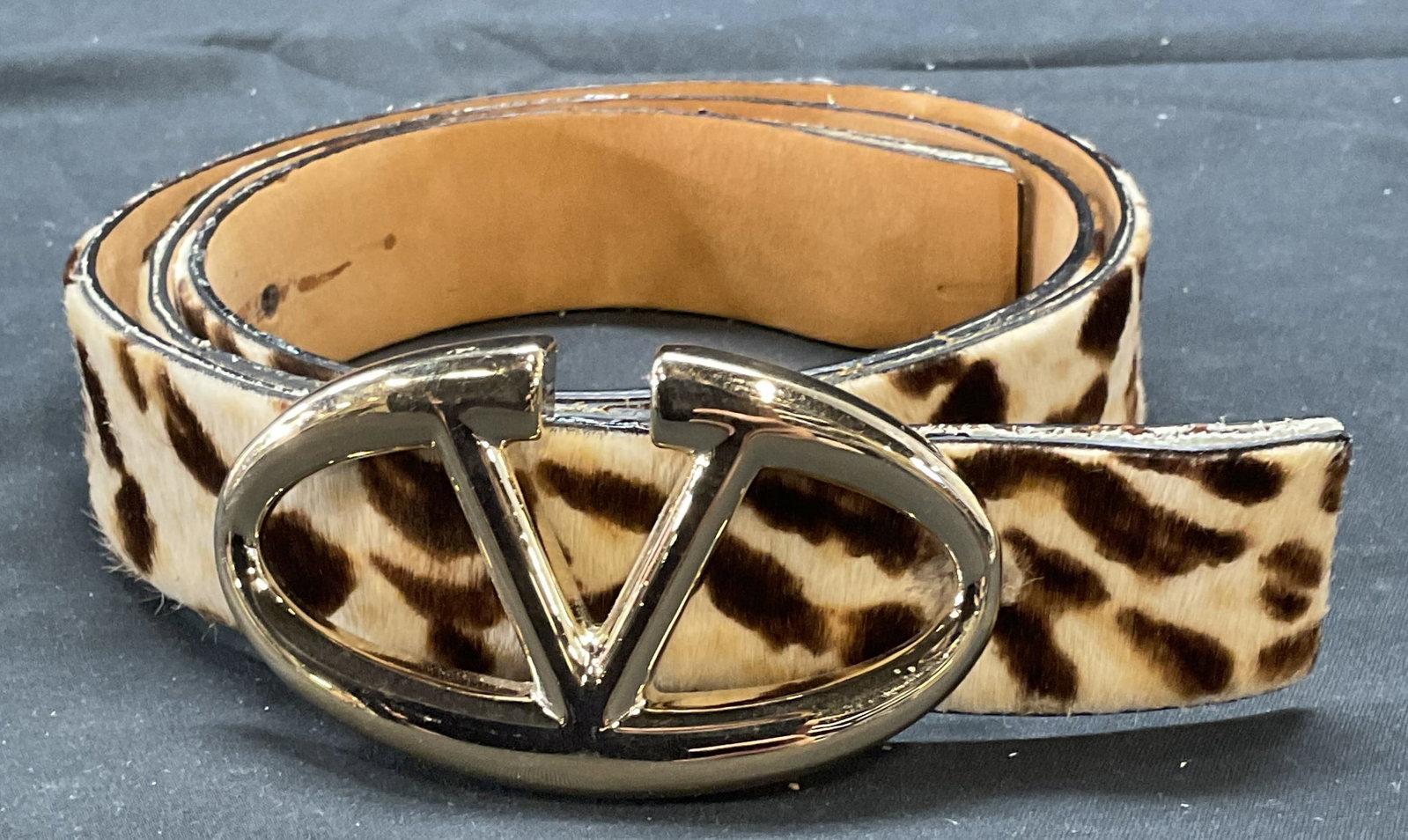 Valentino Animal Print Fur Belt, Italy: Valentino Garavani animal print fur belt. Gold tone logo buckle. Signed on leather. Made in Italy. Size 34. Wear to material including separation, blemishes, residue, and shedding observed. Valentino,
