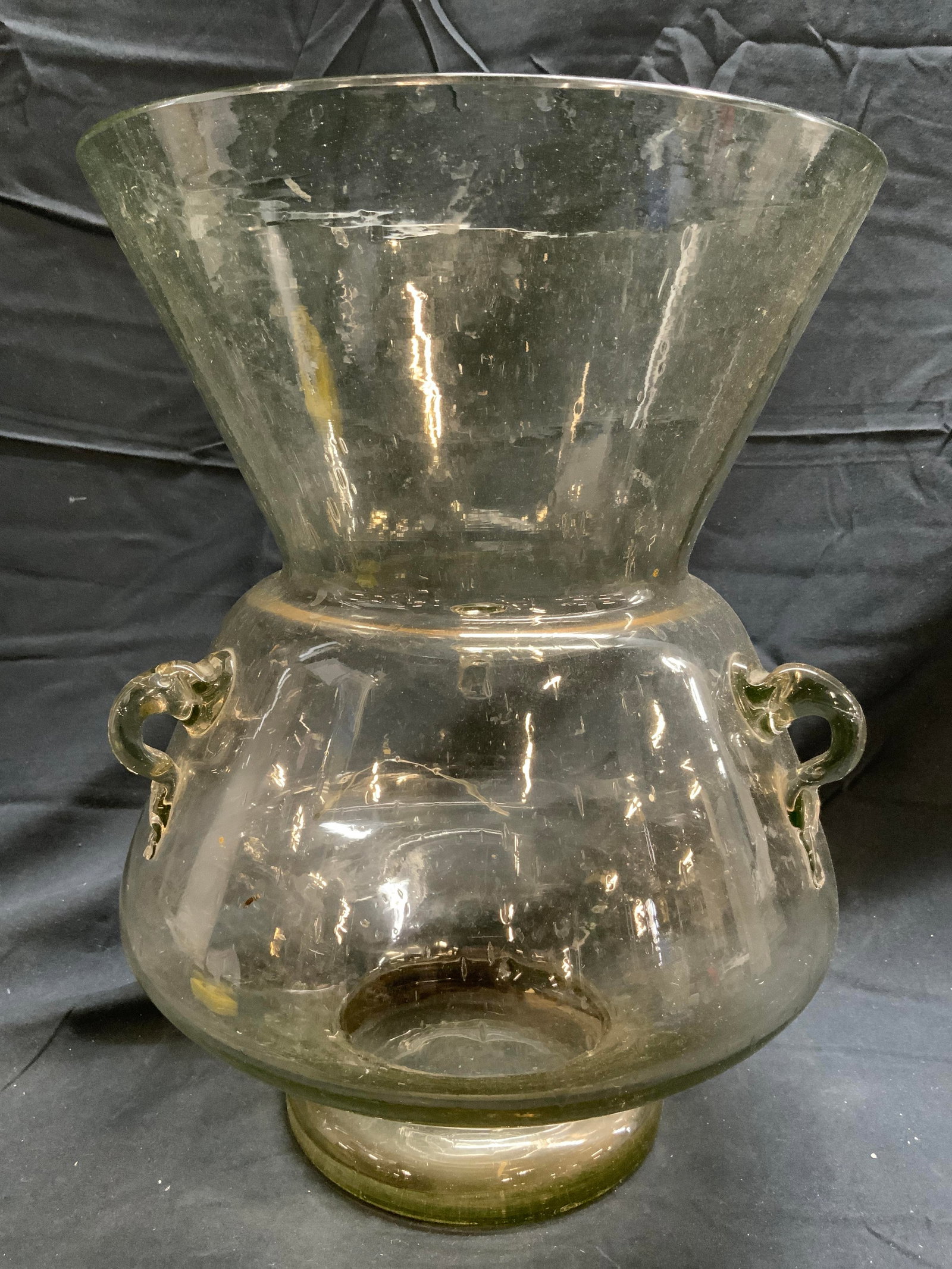 Footed Art Glass Vase W Handles: Vase is glass, possibly handblown. Piece appears to possibly be Murano (No apparent markings). Vase is has 3 molded handles. Vase is footed. Piece expands from neck to rim. Piece measures approximatel