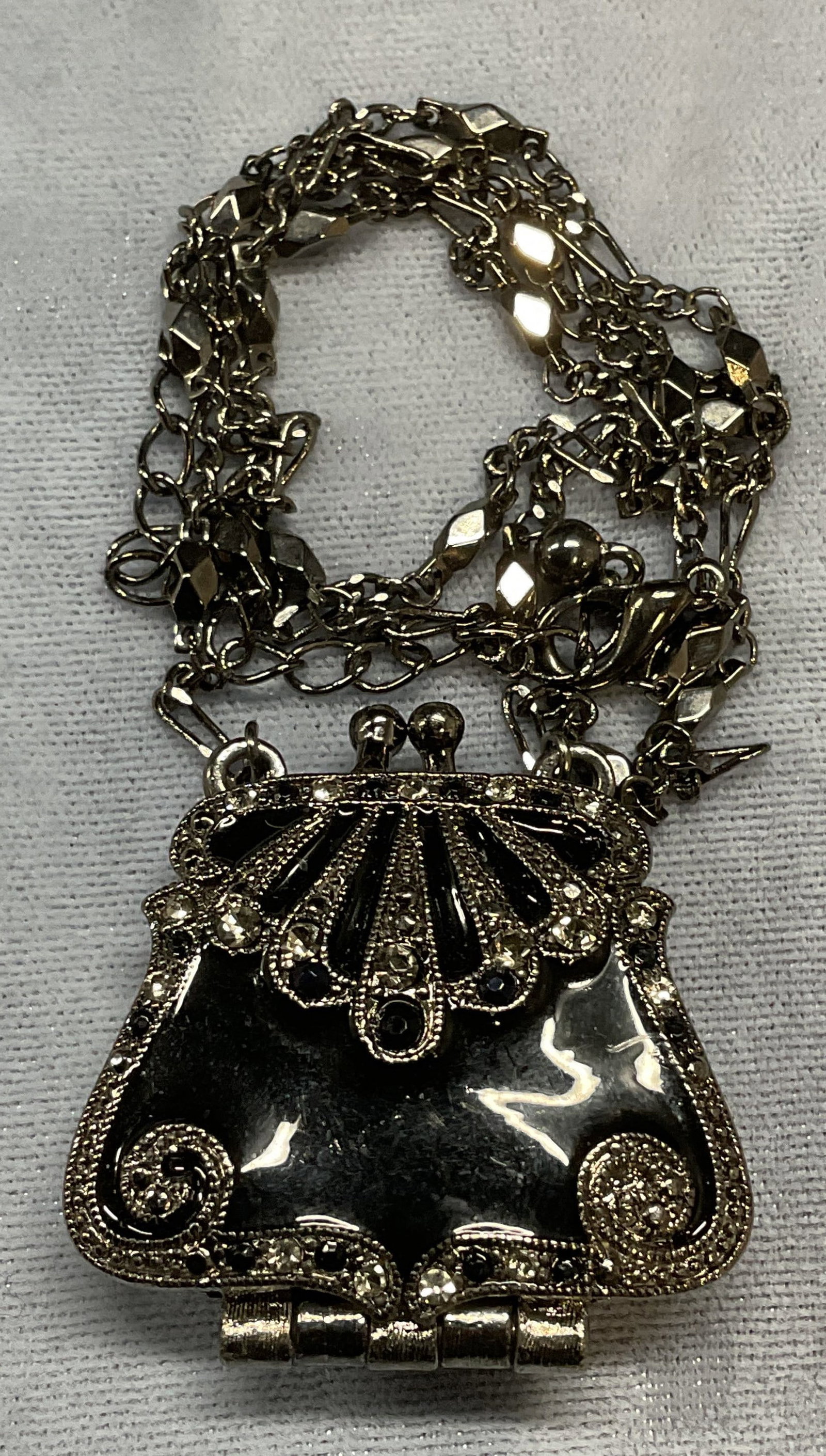 Silver Tn Enamel Crystal Purse Locket Necklace: Silver tone crystal decorated necklace with purse motif enameled and crystal decorated locket pendant. Drop length approx. 11.75 inches. Locket measures approx. 1.25 x 1.25 inches. Some surface wear i